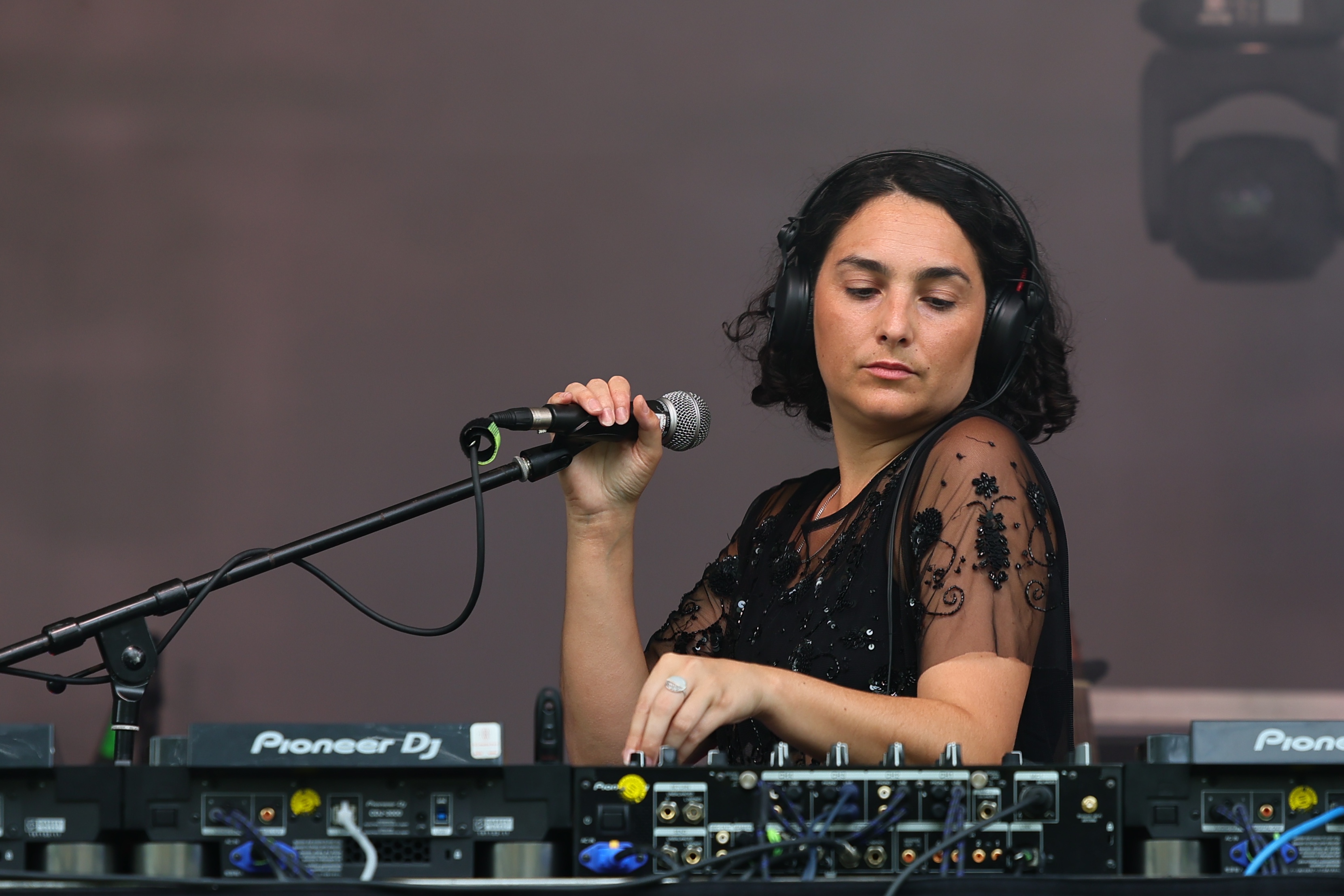 Anna Lysis steht beim CHANCE Festival hinter ihrem DJ-Pult und hält ein Mikrofon