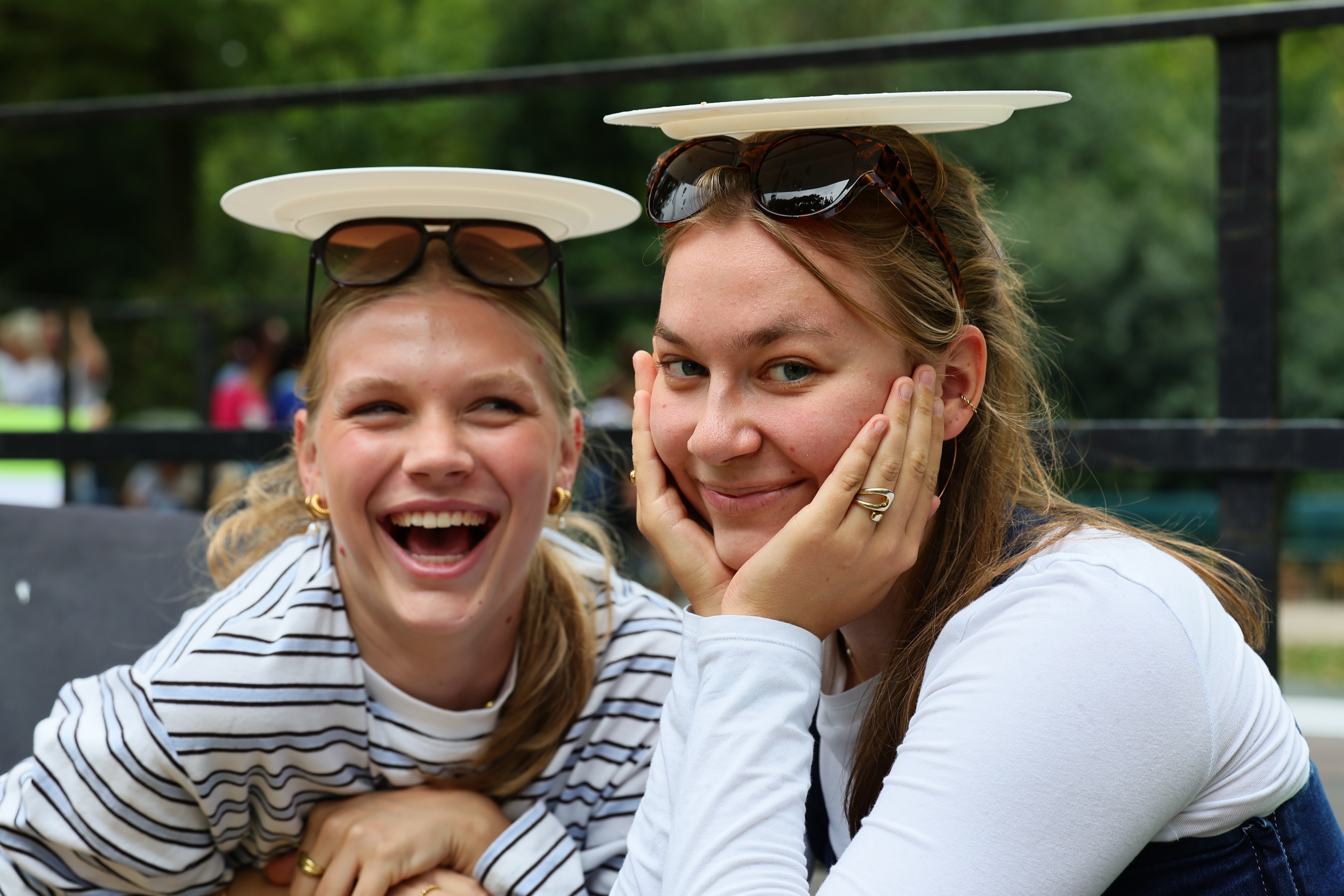 Zwei lachende Besucherinnen balancieren Frisbeescheiben auf ihren Köpfen