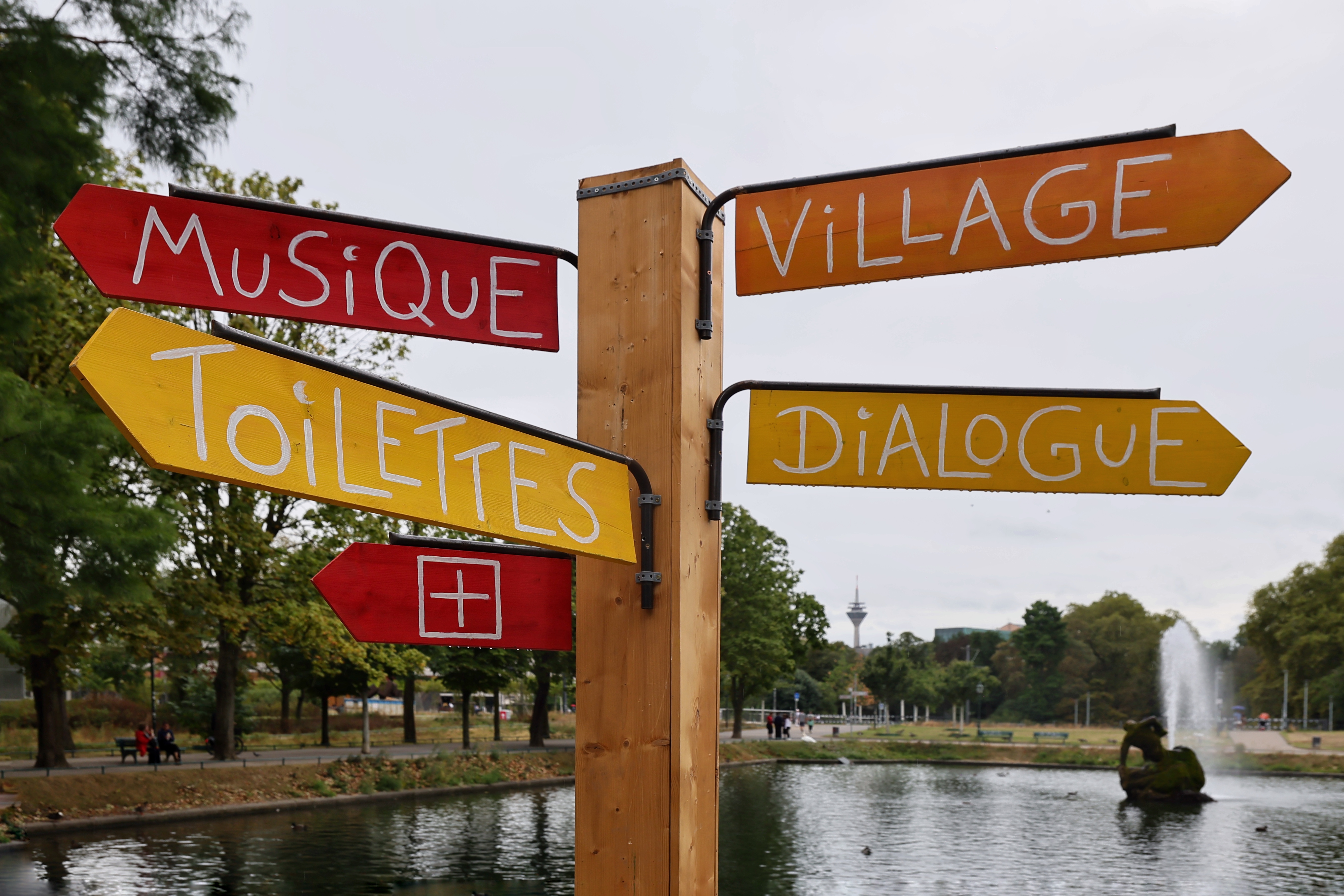 Ein bunter Wegweiser im Hofgarten zeigt zu Musique, Toilettes, Village und Dialogues