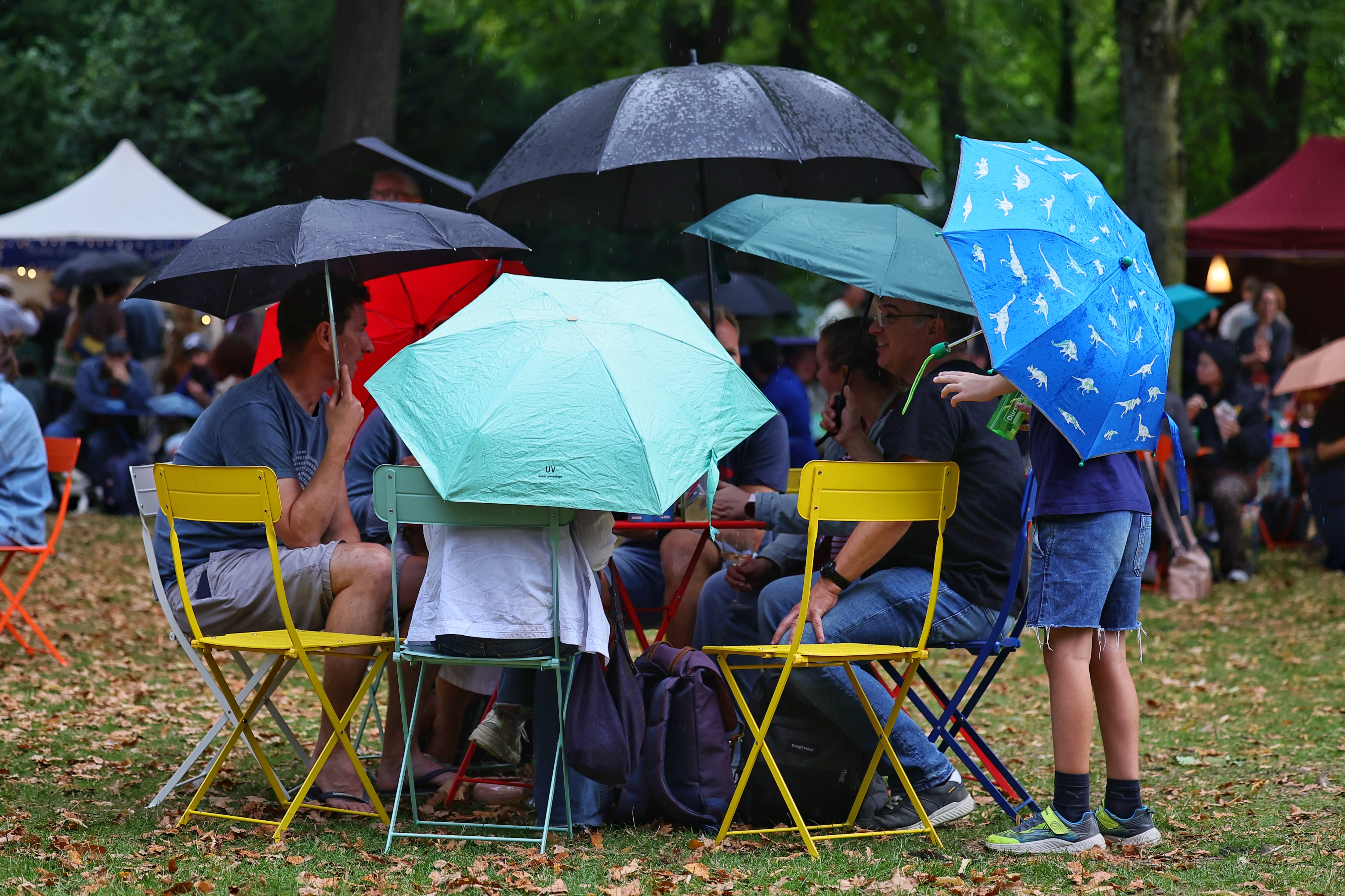 Besucherinnen und Besucher sitzen unter bunten Regenschirmen vor der Bühne des CHANCE Festivals im Düsseldorfer Hofgarten