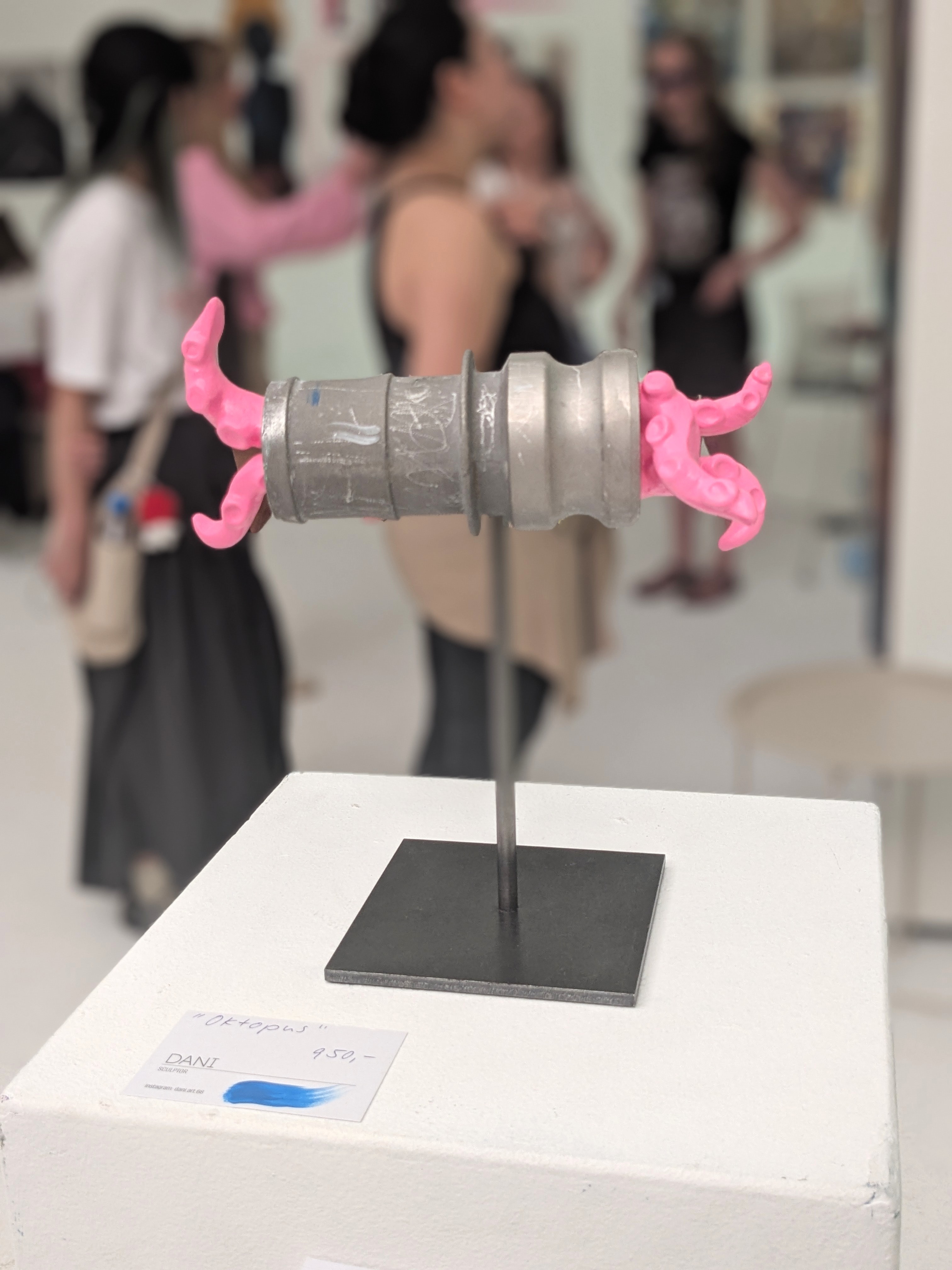 Metallskulptur mit pinken Tentakeln auf einem Sockel, davor ein Preisschild mit der Aufschrift Oktopus 950