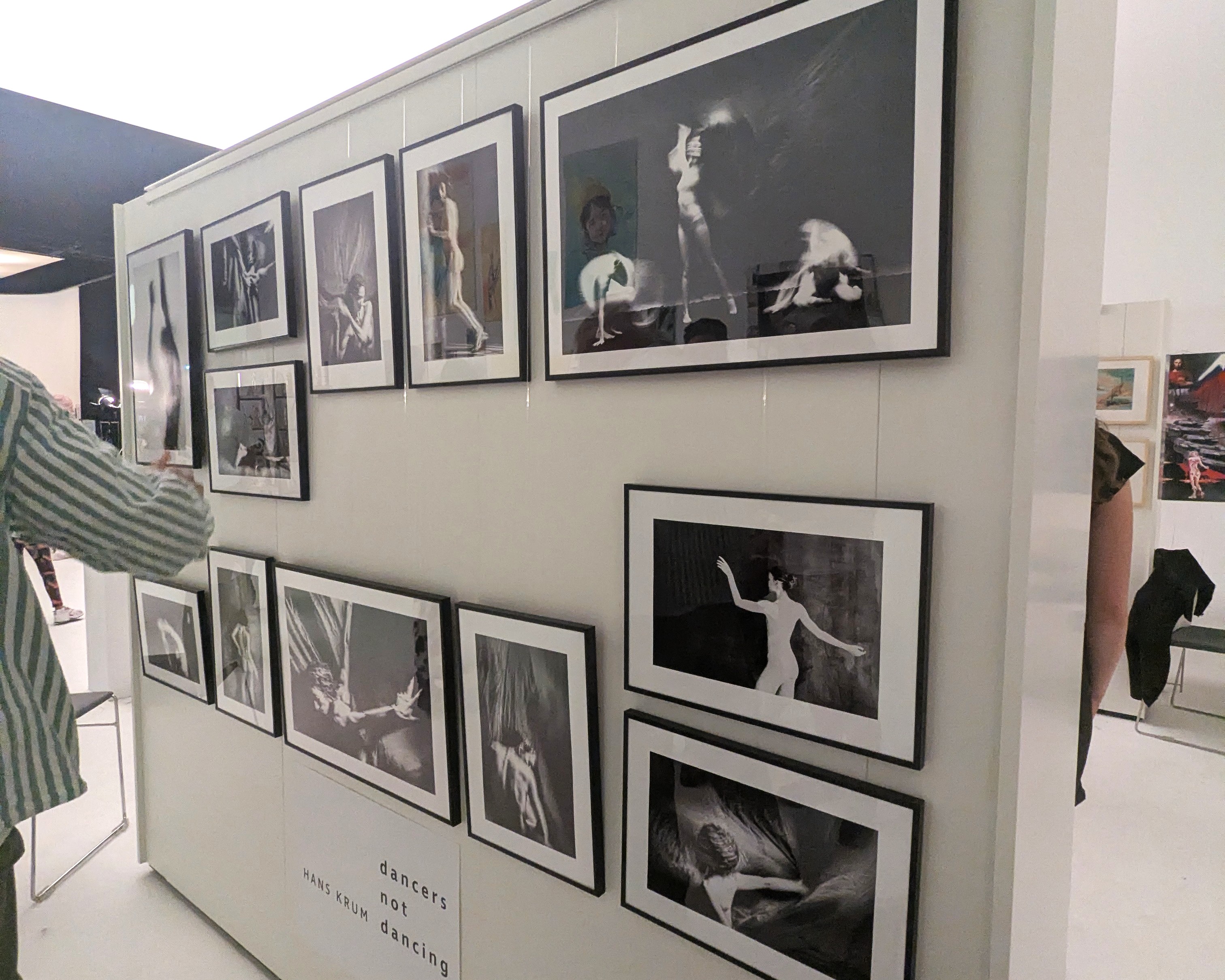 Mehrere gerahmte Schwarz-Weiß-Fotografien tanzender Körper an einer Wand, darunter ein Schild mit der Aufschrift dancers not dancing, Hans Krum