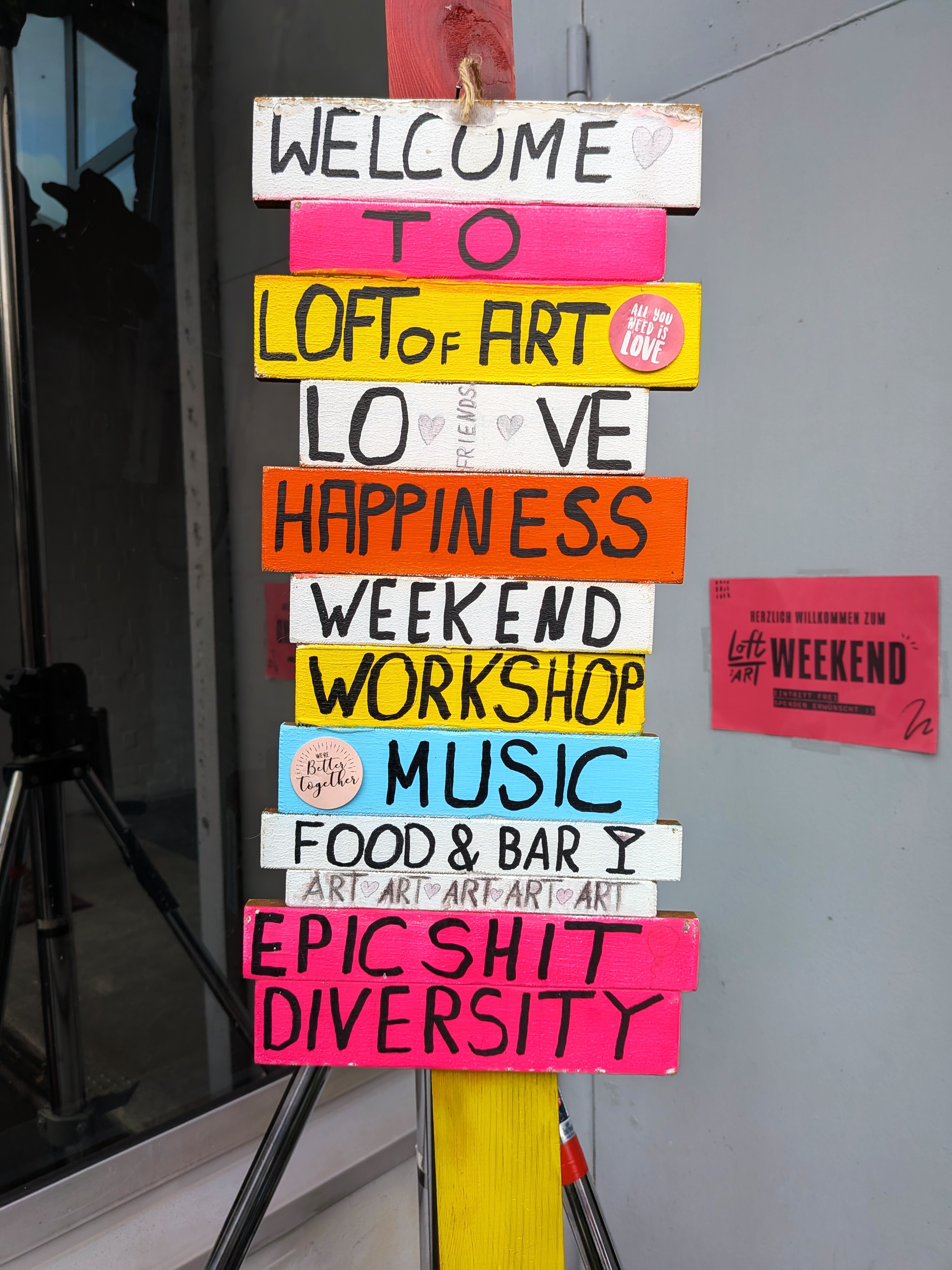 Buntes Holzschild mit handgemalten Wörtern wie Welcome, Loft of Art und Happiness