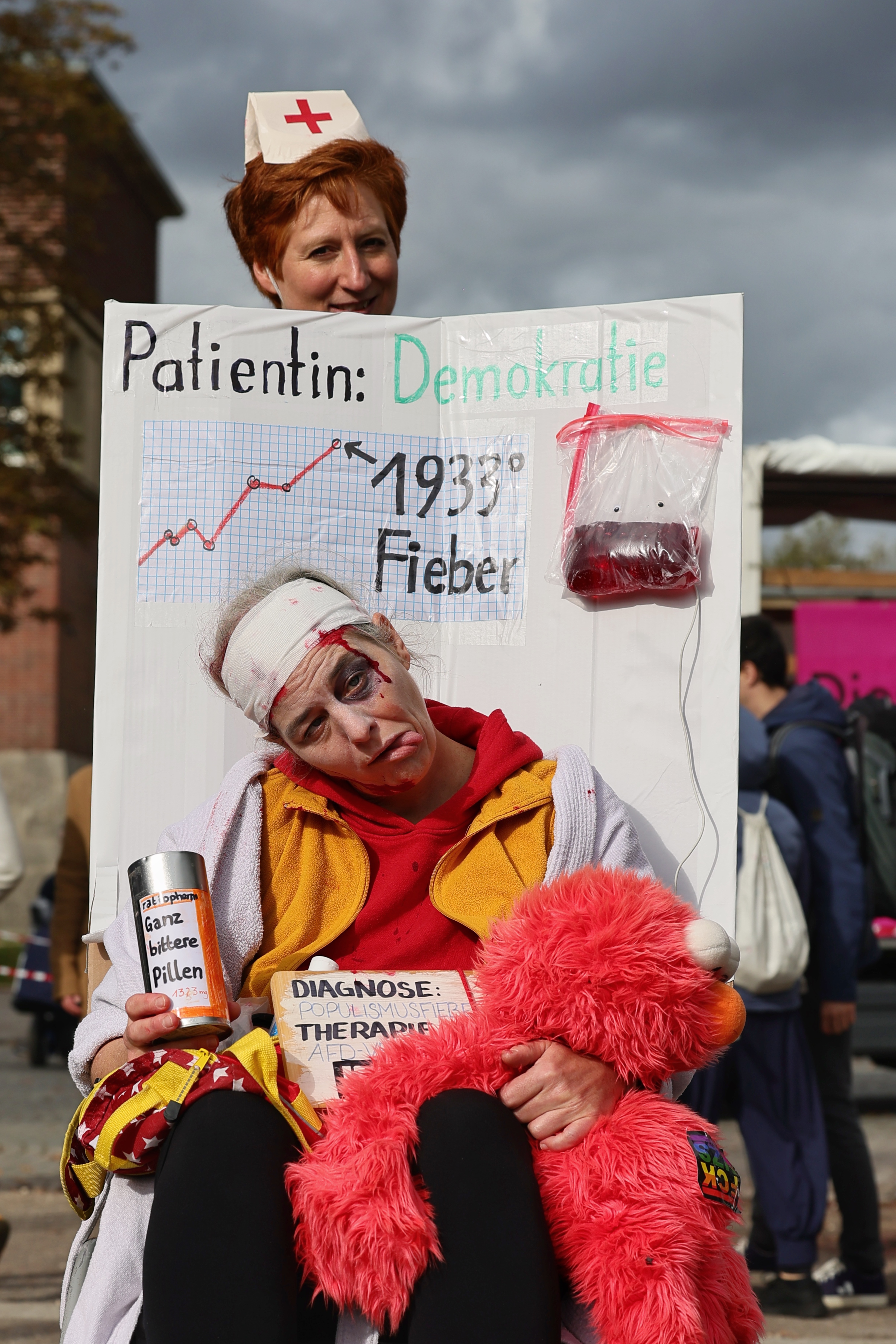 Kostümierte Demonstrationsteilnehmerin mit dem Schild Patientin Demokratie