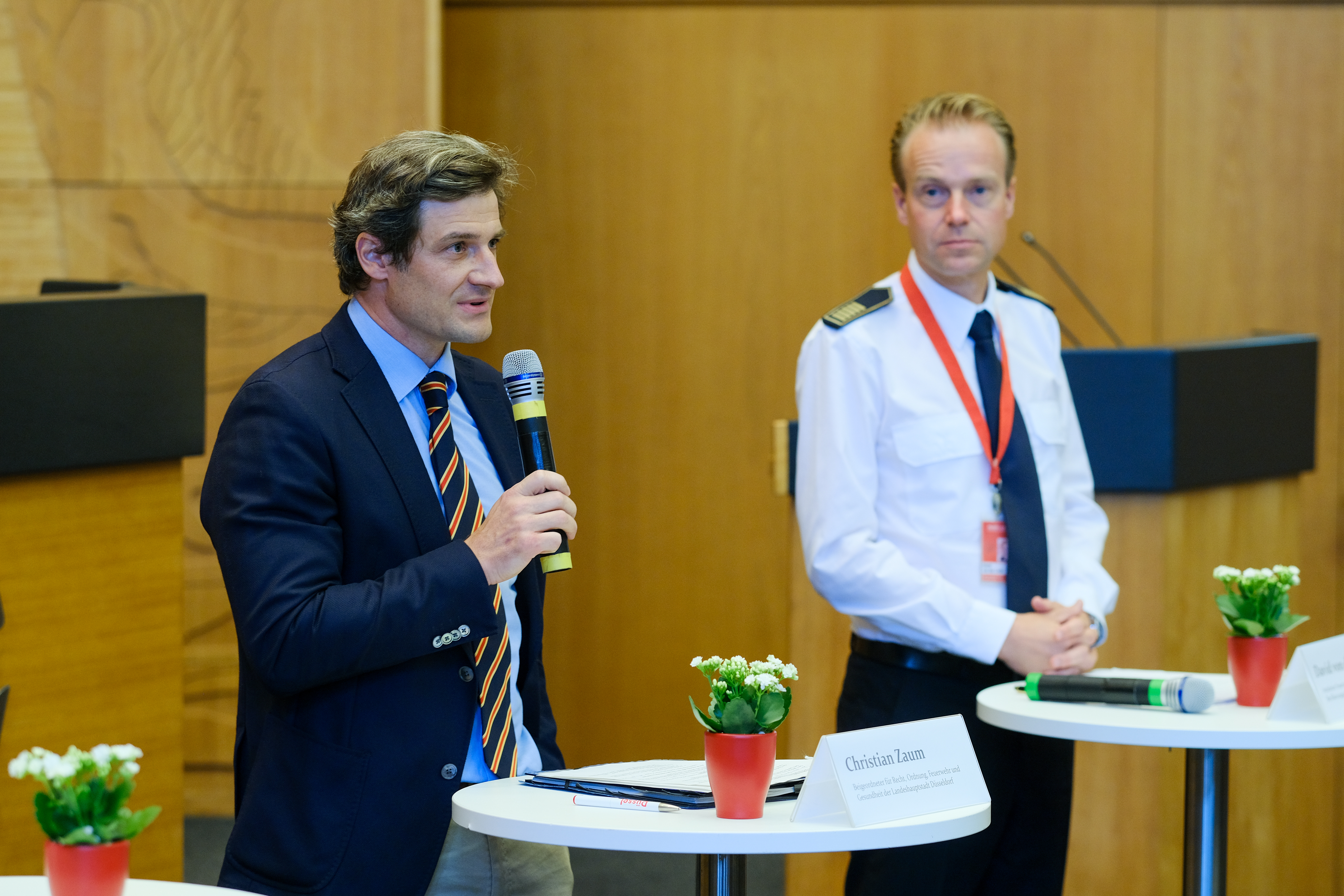 Der Beigeordnete für Recht, Ordnung, Gesundheit und Feuerwehr, Christian Zaum (li.) und Feuerwehrchef David von der Lieth informierten die Teilnehmenden im Plenarsaal über Details zum Hochwasserschutz © Landeshauptstadt Düsseldorf, Michael Gstettenbauer 