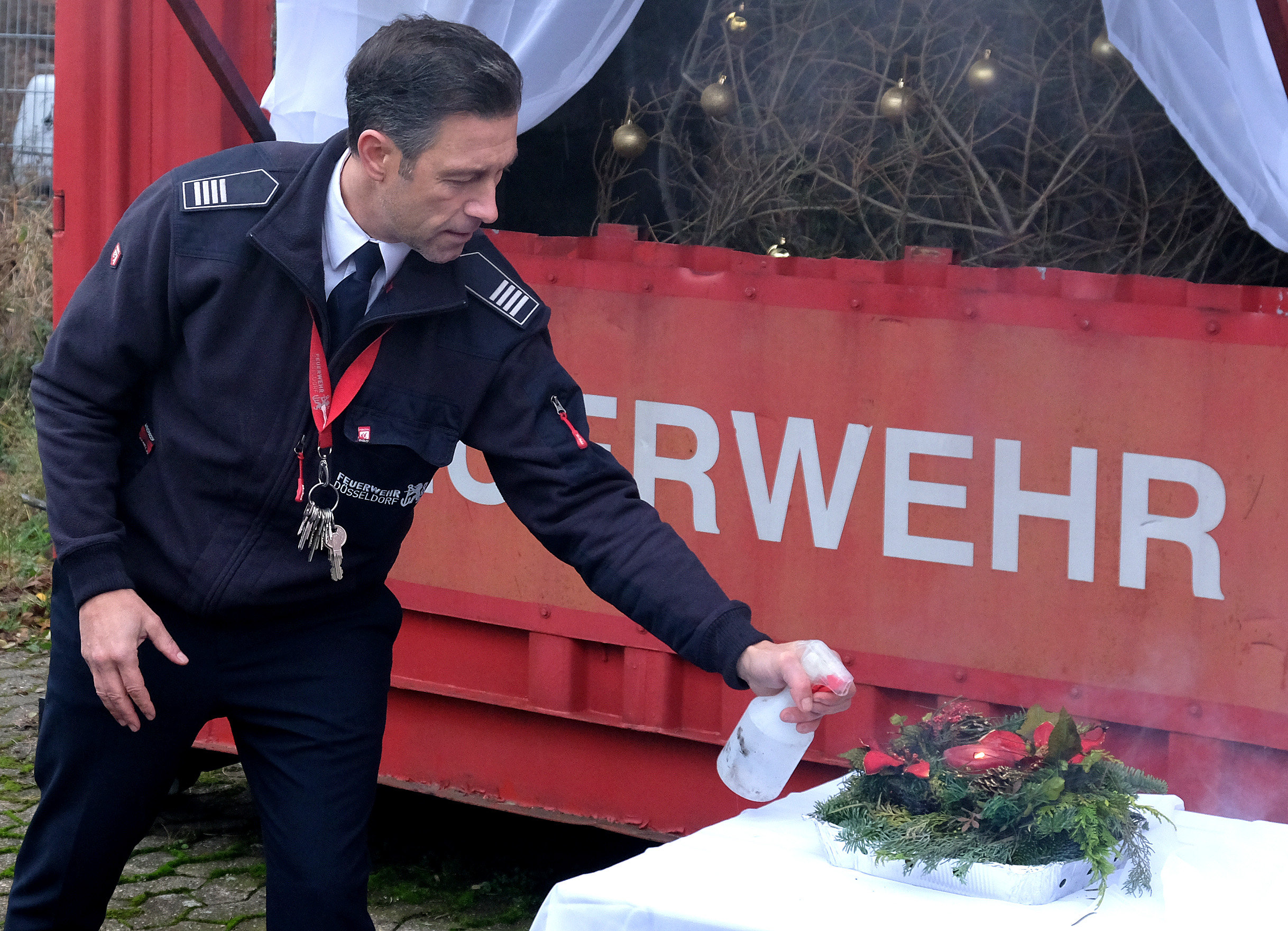 Marcel Angenendt von der Feuerwehr Düsseldorf demonstriert das Löschen eines brennenden Adventsgesteckes © Landeshauptstadt Düsseldorf/Wilfried Meyer 