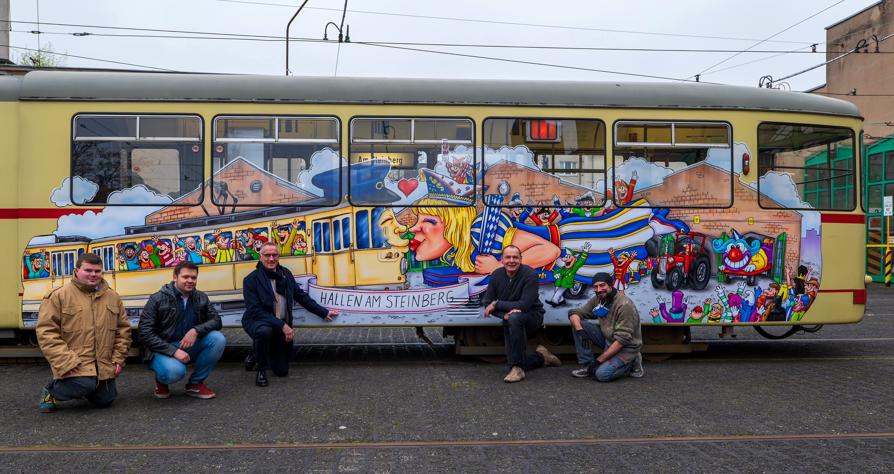 Die Steinberg-Wimmelbahn präsentieren David Zieren und Julian Zimmermann (beide vom Vorstand der Linie D, Arbeitsgemeinschaft historischer Nahverkehr e.V.), Klaus Klar (Vorstandsvorsitzender und Arbeitsdirektor der Rheinbahn), Jacques Tilly und David Salomo aus dem Team der Wagenbau-Künstler./ Foto © Rheinbahn