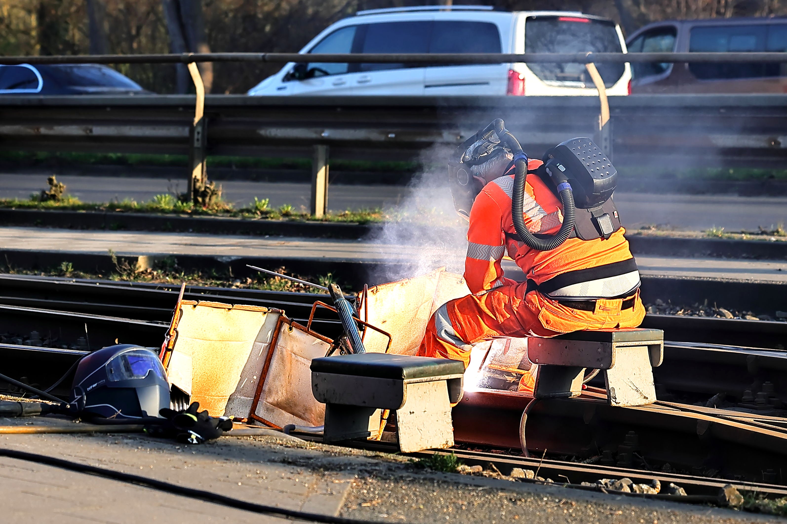 Ein Mitarbeiter in orangefarbener Schutzkleidung führt Schweißarbeiten an Straßenbahngleisen in Düsseldorf aus.