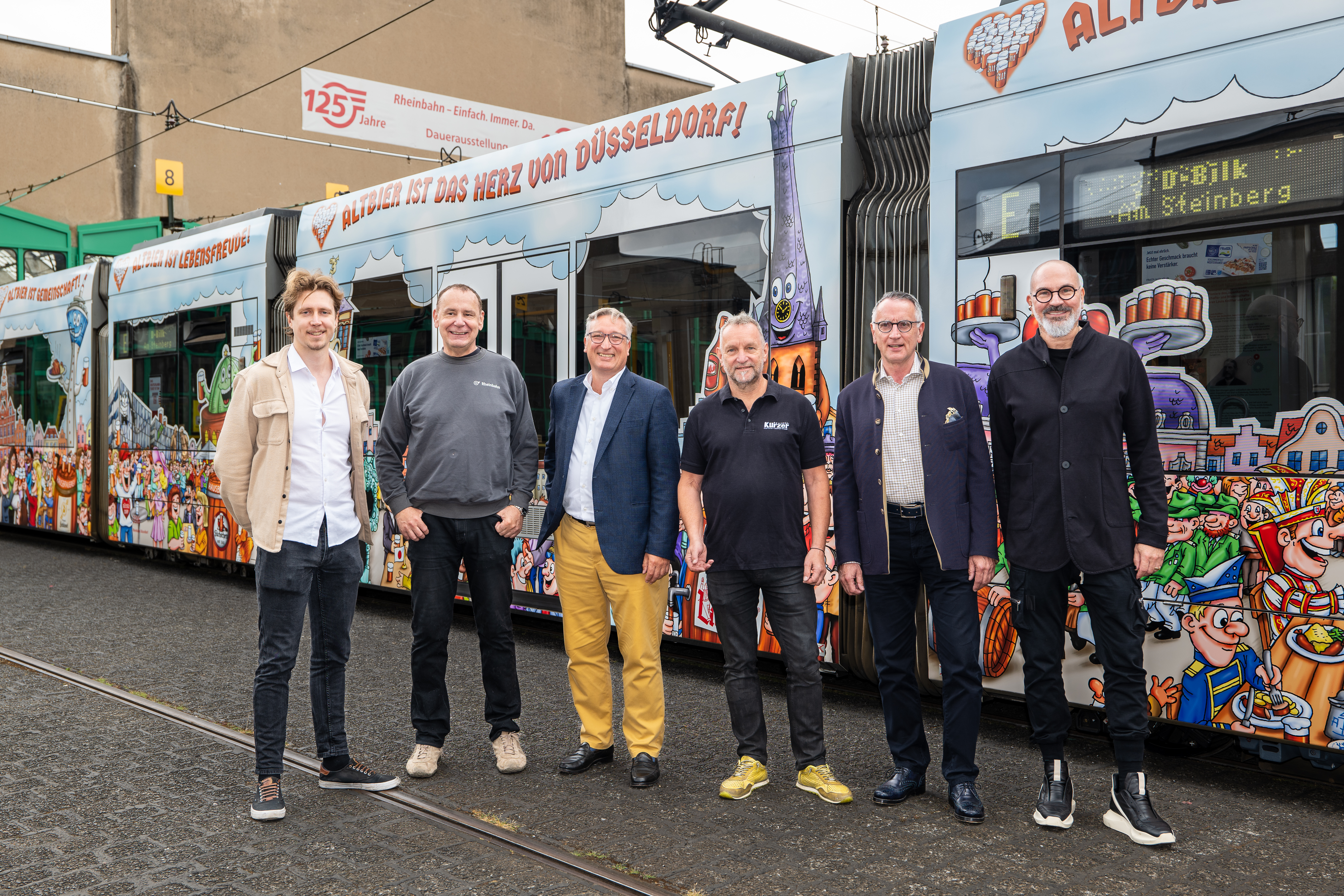 Vertreterinnen und Vertreter der Düsseldorfer Hausbrauereien Füchschen, Kürzer, Schlüssel, Schumacher und Uerige sowie Jacques Tilly, Andreas Hartnigk, Aufsichtsratsvorsitzender der Rheinbahn, und Klaus Klar stießen am Montagmittag auf die neue Altbier-Bahn an und gaben ihr das Abfahrtsignal / Foto: Rheinbahn