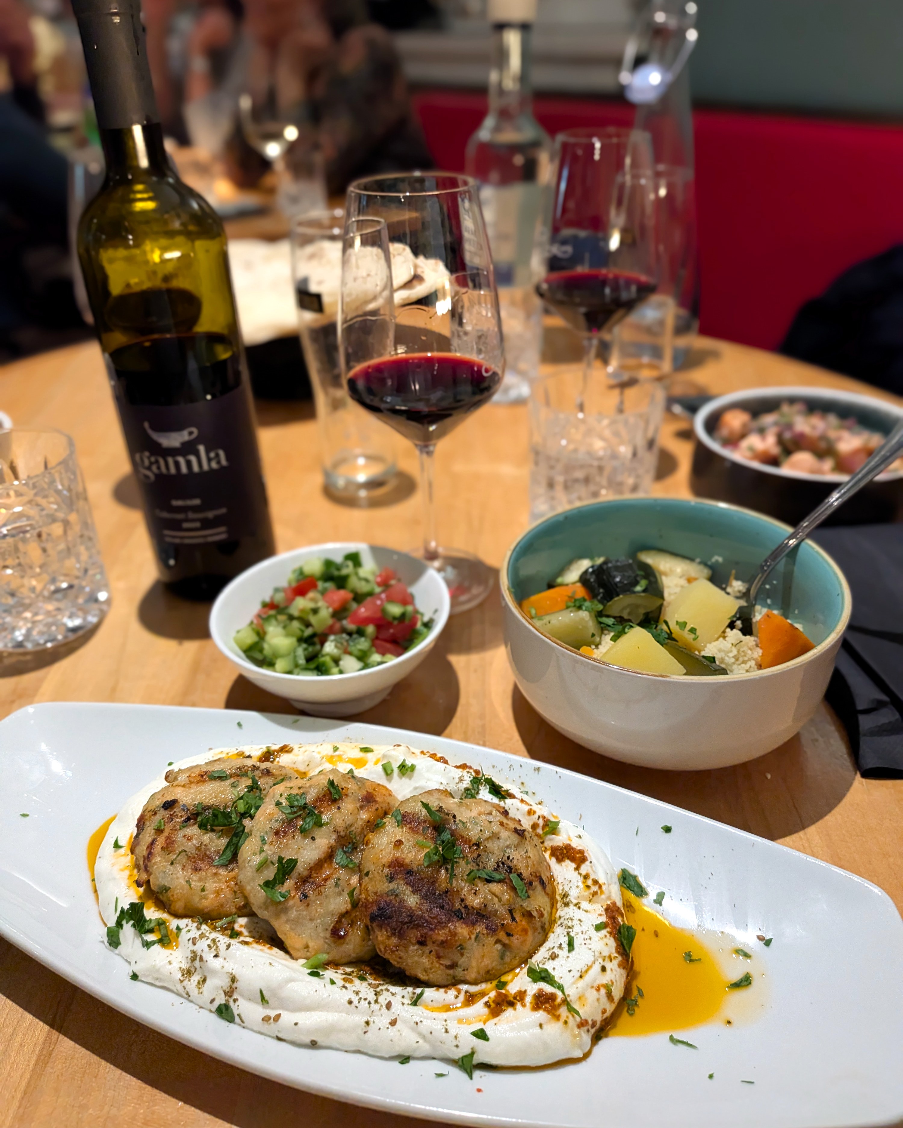 Fischkebab auf Labaneh mit Harissaöl, dazu Couscous mit Gemüse und israelischer Salat bei Die Kurve in Düsseldorf.