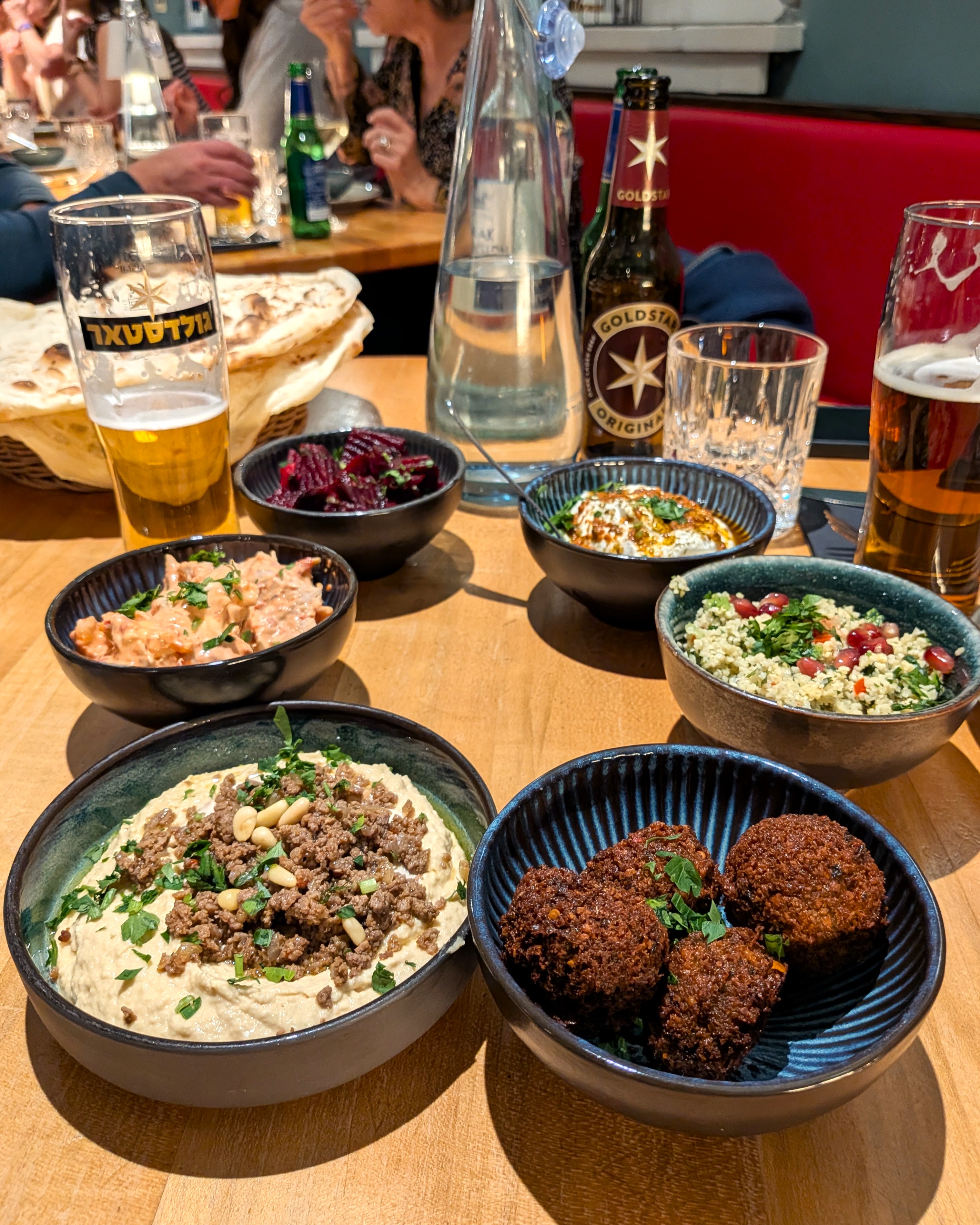 Sechs Mezze mit Labaneh, Spicy Chicken, Tabouleh, Rote-Bete-Salat, Falafel und Hummus Tartar auf dem runden Tisch bei Die Kurve.