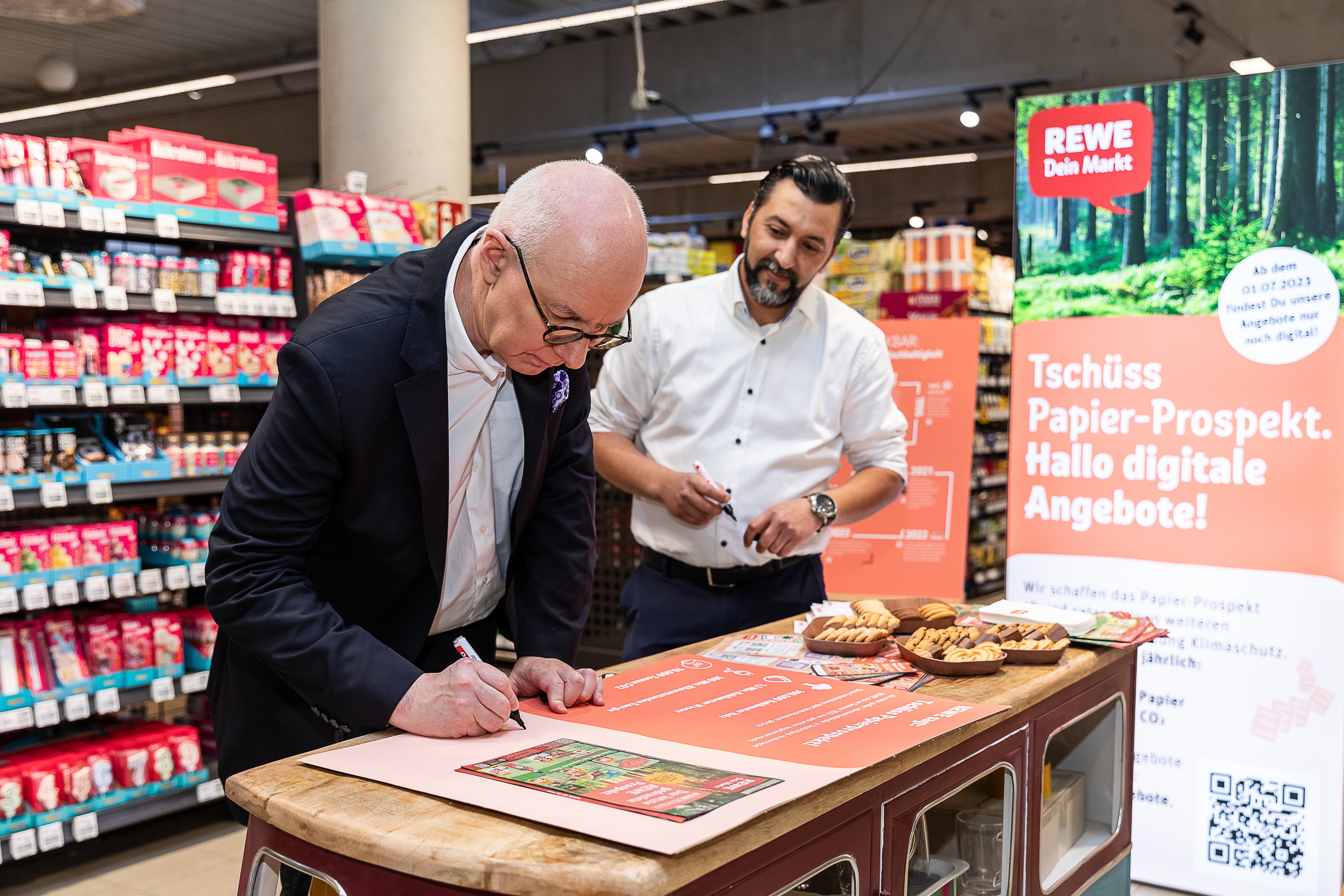 Hanno Rieger, Vorsitzender der Geschäftsleitung REWE Region West (links) und Yassine Fakhouri, REWE-Kaufmann aus Düsseldorf, unterschrieben zum Abschied den letzten gedruckten Prospekt / Foto: REWE, Yassine Fakhouri 