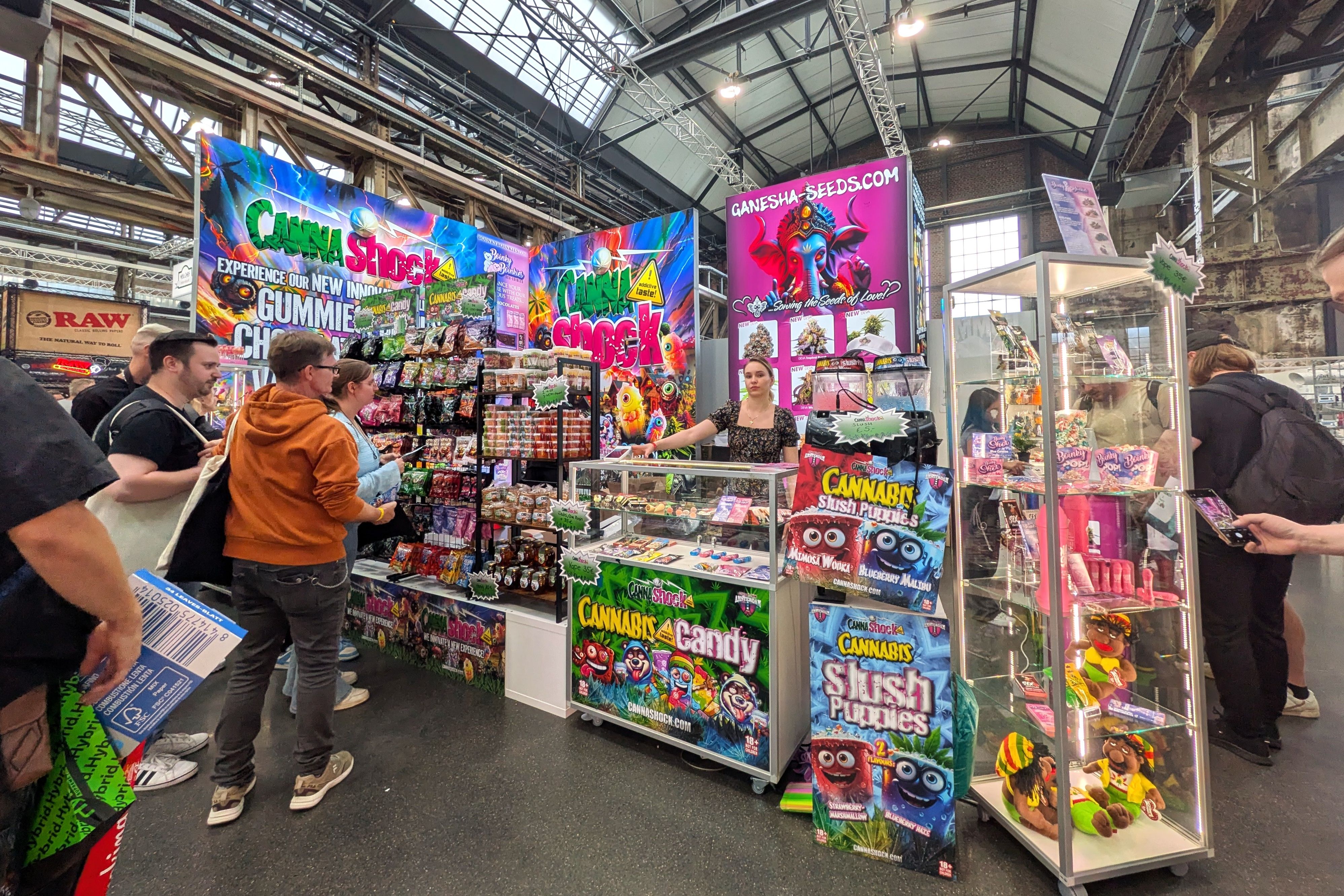 Besucher stehen vor einem farbenfrohen Messestand mit Fruchtgummis, Bonbons und Produkten in auffälliger Süßwarenoptik.