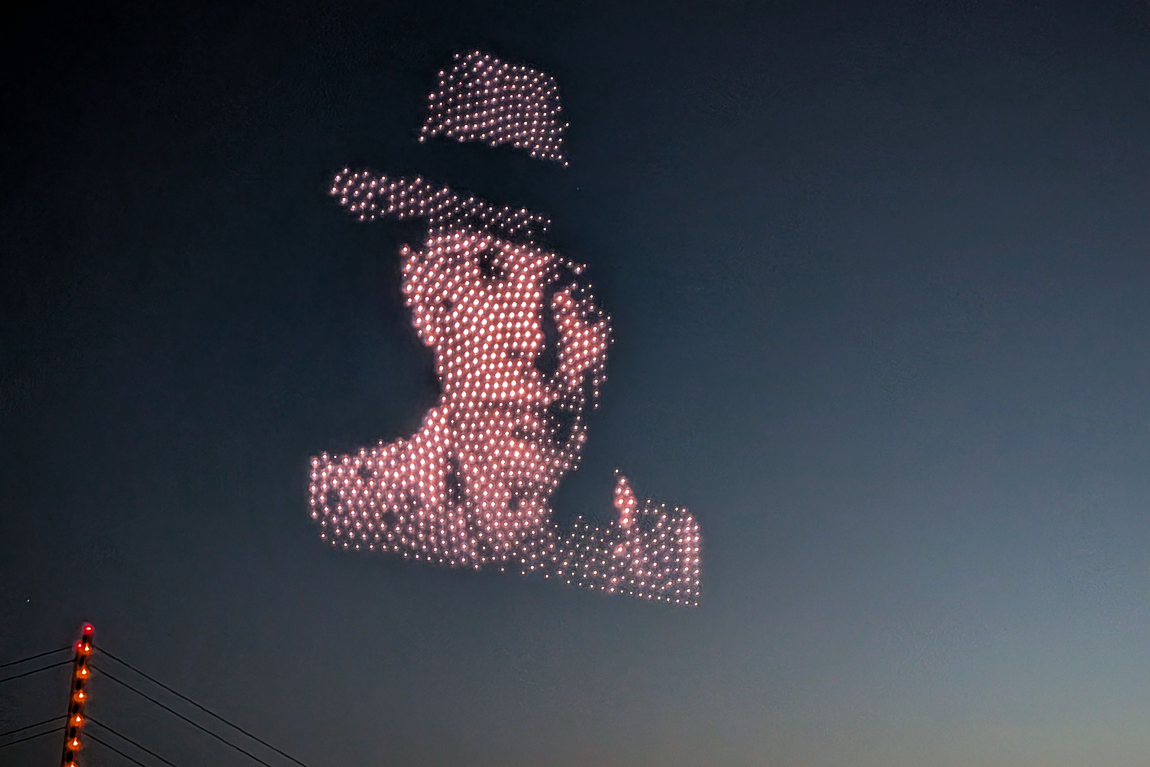 Aus Lichtpunkten geformtes Motiv von Joseph Beuys mit Hut über der Rheinkniebrücke in Düsseldorf