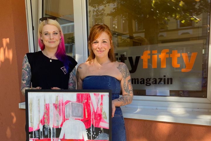 "Nie wieder ist jetzt" - Jana Rosnowski, Sozialarbeiterin bei fiftyfifty (l.) nahm das Bild von Broilers Bassistin Ines Maybaum entgegen. (Foto: fiftyfifty)