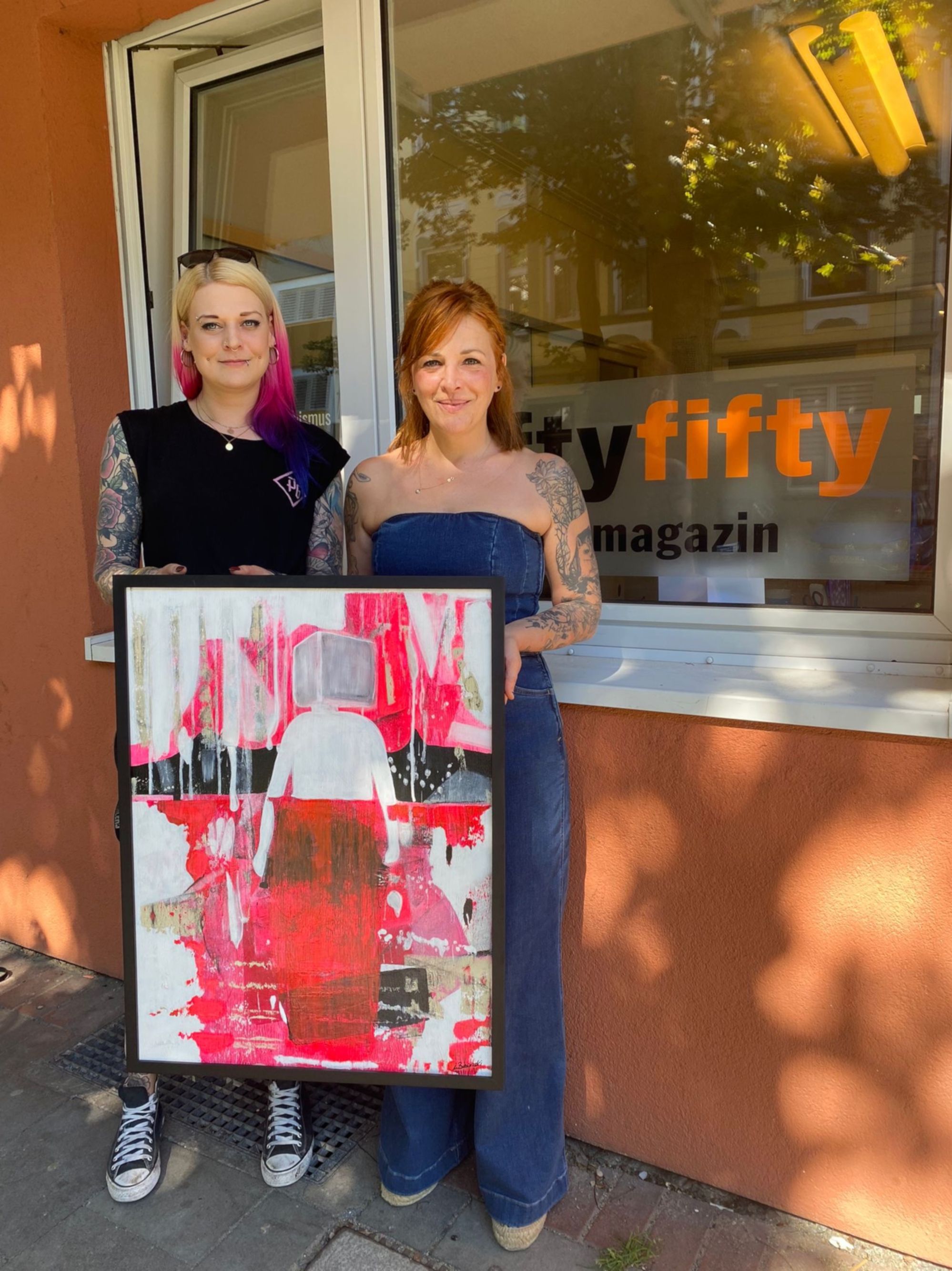 Jana Rosnowski, Sozialarbeiterin bei fiftyfifty (l.) nahm das Bild von Broilers Bassistin Ines Maybaum entgegen. (Foto: fiftyfifty)