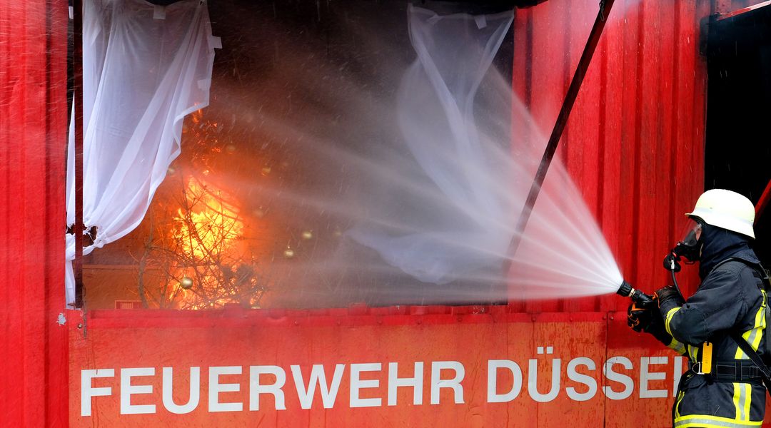 Ein Feuerwehrmann löscht den brennenden Weihnachtsbaum © Landeshauptstadt Düsseldorf/Wilfried Meyer 