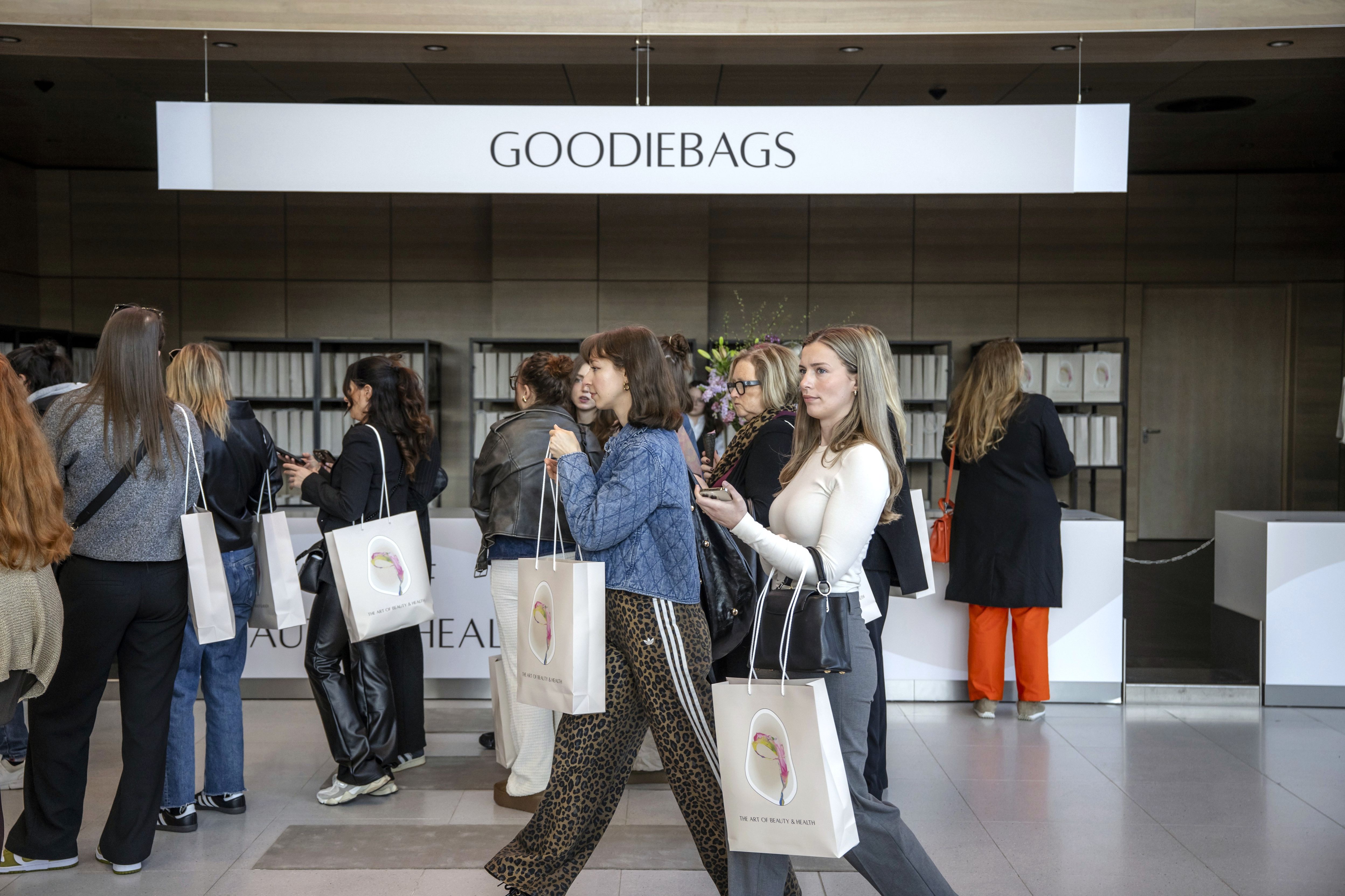 Besucherinnen und Besucher holen Goodiebags bei The Art of Beauty & Health im Eingangsbereich der Messe Düsseldorf ab.