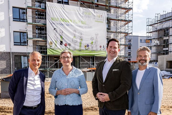 Alexander Rychter (Verbandsdirektor des Verbands der Wohnungs- und Immobilienwirtschaft Rheinland Westfalen e. V.), Klara Geywitz (Bundesministerin für Wohnen, Stadtentwicklung und Bauwesen), Niels Klein (Vorstand der Düsseldorfer Bau- und Spargenossenschaft eG) und Dipl.-Ing. Peter Malchartzeck (Architektenbüro MIKSCH RÜCKER MALCHARTZECK ARCHITEKTEN) im Sonnenblumenfeld der DüBS (v.l.n.r.).