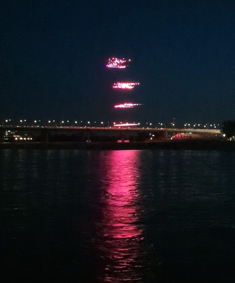Rosafarben leuchtende Drohnen kehren nach der Show zu ihrem Startplatz auf den Oberkasseler Rheinwiesen zurück