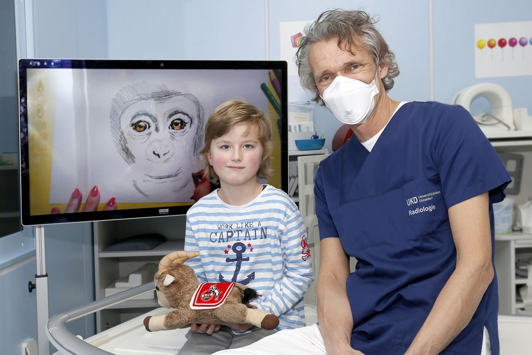 „Wir haben in der Kinderradiologie verschiedene Möglichkeiten mit denen wir die Untersuchung angenehmer gestalten können. Dazu gehört unser Fernseher auf dem wir Zeichentrickfilme, Bastelanleitungen und andere Arten von Videos abspielen können“, erklärt Dr. Dirk Klee Leiter der Kinder- und Jugendradiologie an der Uniklinik Düsseldorf /Foto Dr. Dirk Klee mit Emil ©UKD