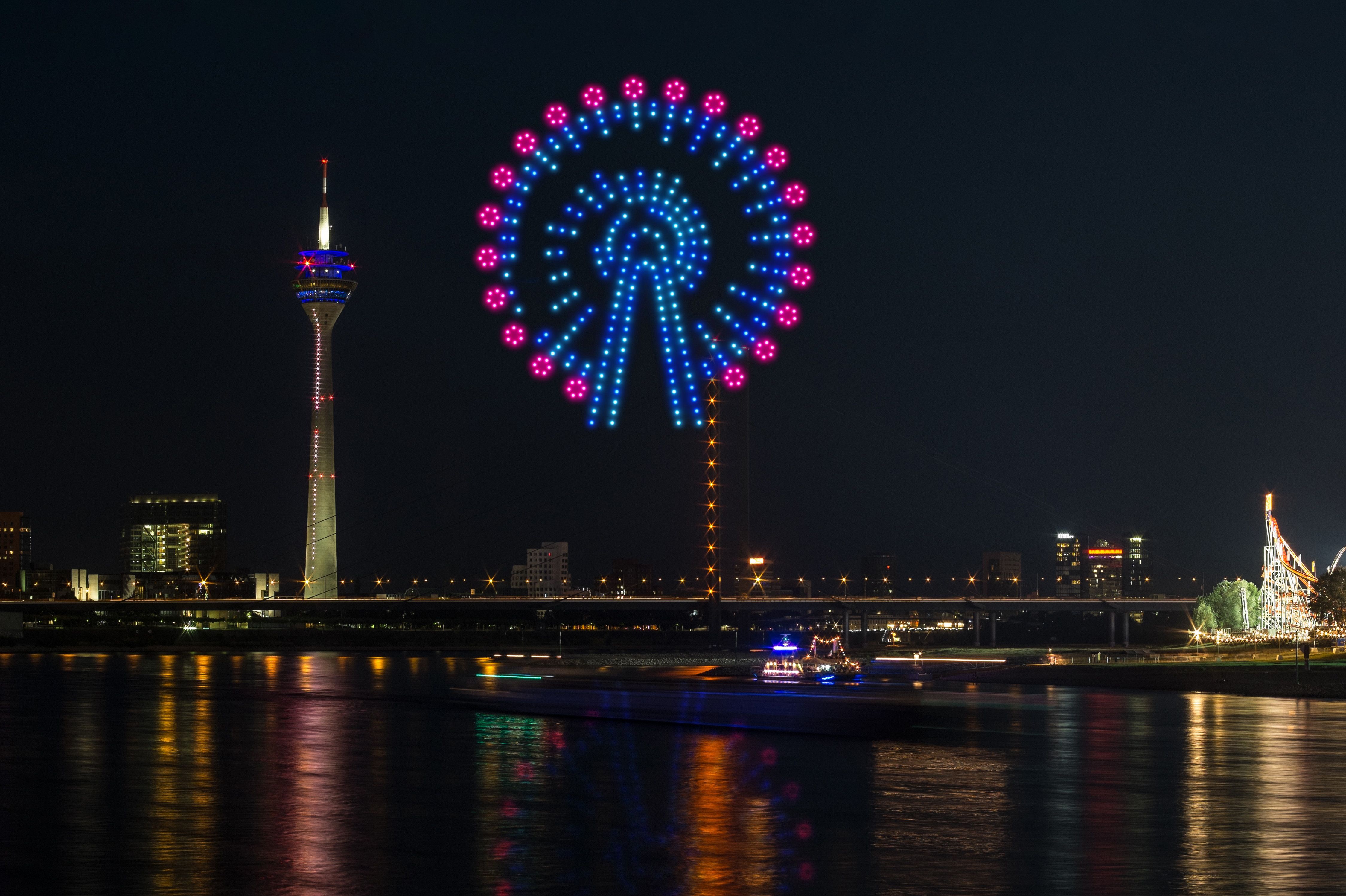 Riesenrad aus Lichtpunkten: Bei der AO-Drohnenshow zur Rheinkirmes 2025 entsteht über dem Rhein ein digitales Abbild des Jahrmarkt-Klassikers – mit dem Düsseldorfer Fernsehturm im Hintergrund / Foto: AO Multimedia & Drones 