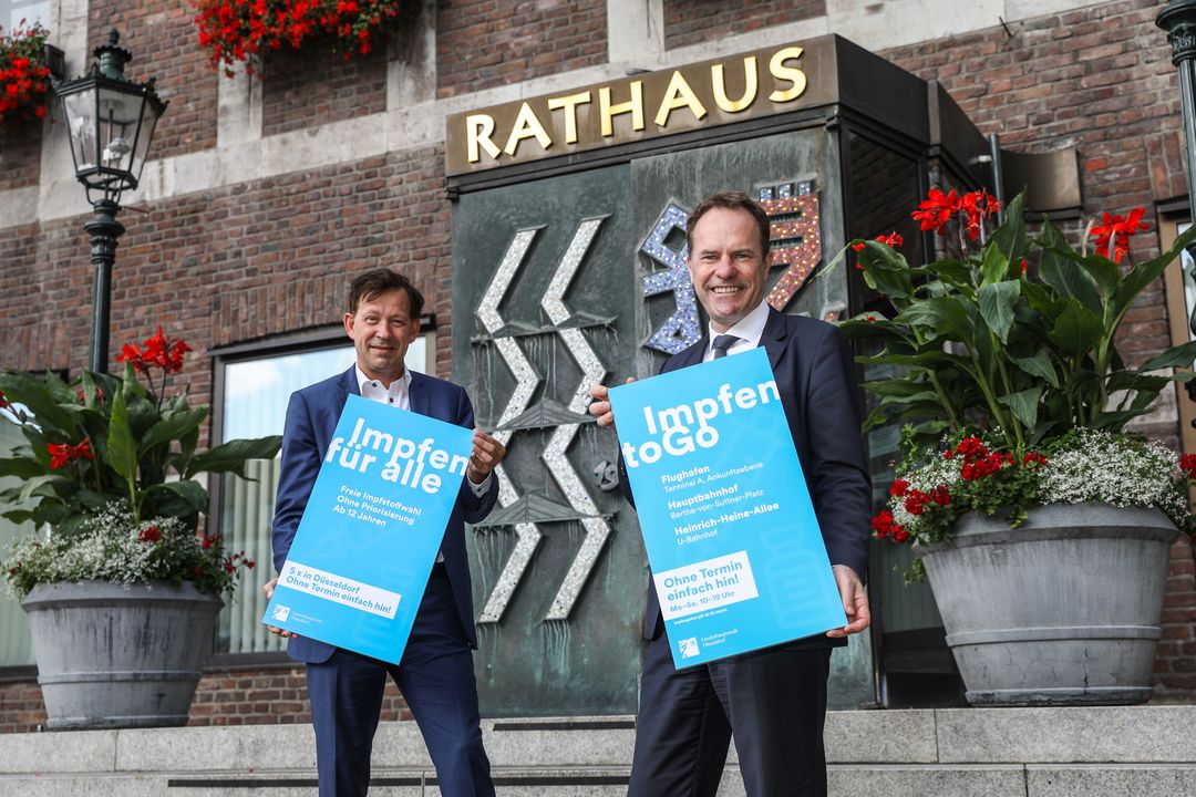 Dr. Stephan Keller (r.) und Stadtdirektor Burkhard Hintzsche mit den neuen Motiven "Impfen für alle" und "Impfen to Go"/ Foto ©Landeshauptstadt Düsseldorf/Melanie Zanin