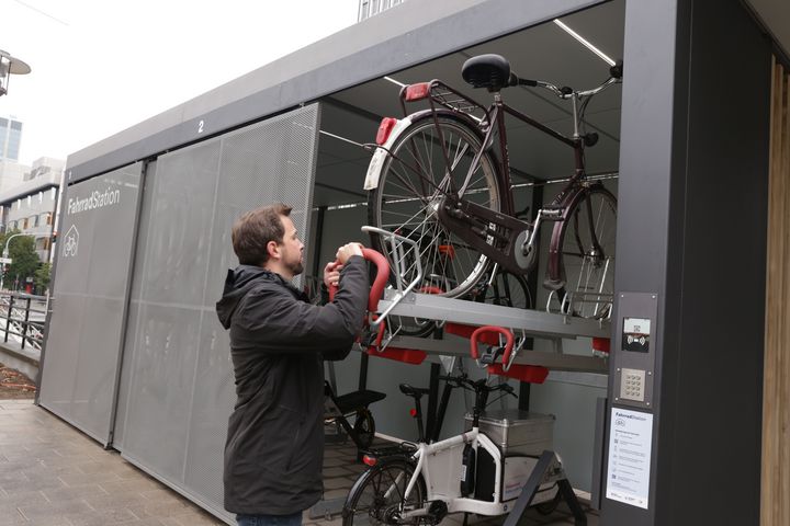Zentrales Modul der Mobilitätsstation ist die Fahrradsammelschließanlage für E-Bikes, Lastenräder und Fahrräder. CMD-Geschäftsführer Dr. David Rüdiger zeigt, wie es geht © Landeshauptstadt Düsseldorf, Ingo Lammert 