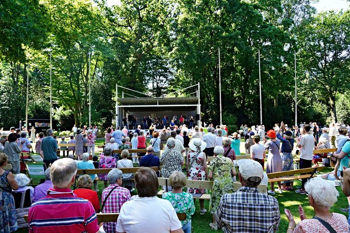 Publikum sitzt und steht bei einem Hofgartenkonzert vor der Bühne im Düsseldorfer Hofgarten.
