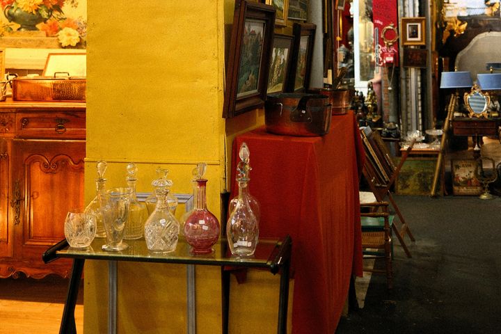 Antiquitäten, Glasvasen, Bilderrahmen und Möbelstücke auf einem Flohmarktstand.