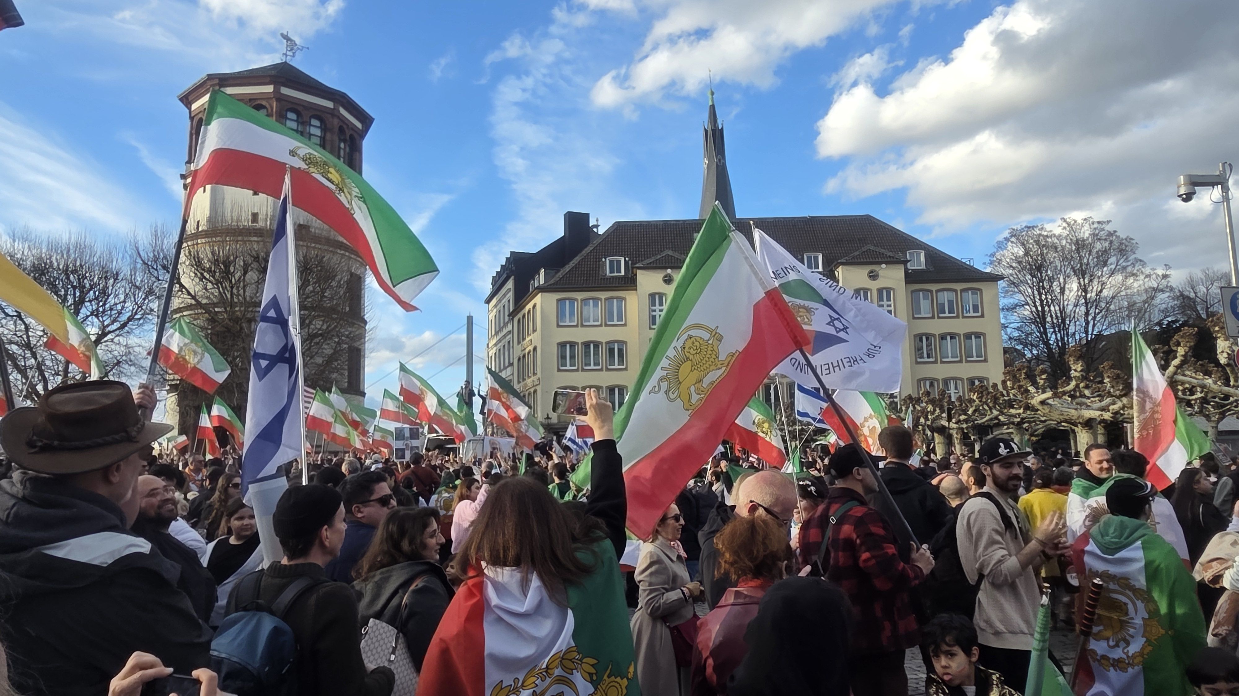 Menschenmenge mit vielen iranischen Fahnen am Burgplatz in Düsseldorf vor dem Schlossturm.