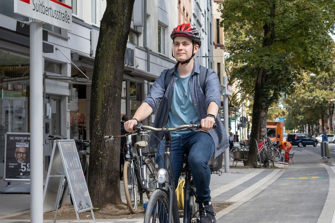 Ein Radfahrer fährt über den angehobenen Radweg an der Haltestelle Suitbertusstraße in Düsseldorf-Bilk
