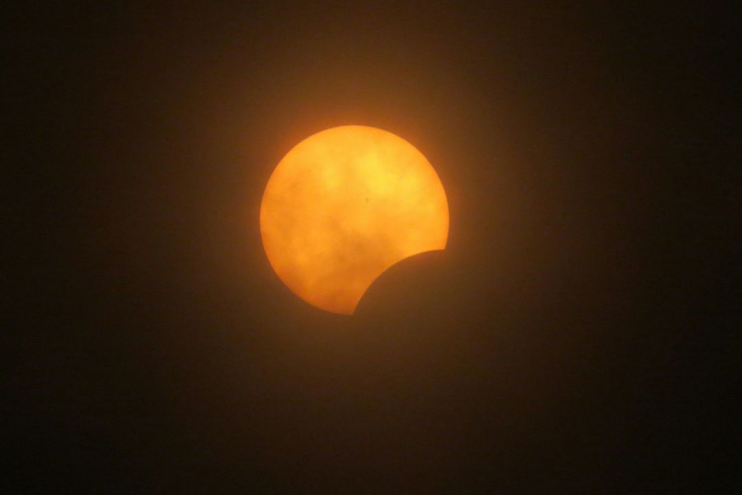 Partielle Sonnenfinsternis mit orange leuchtender Sonne