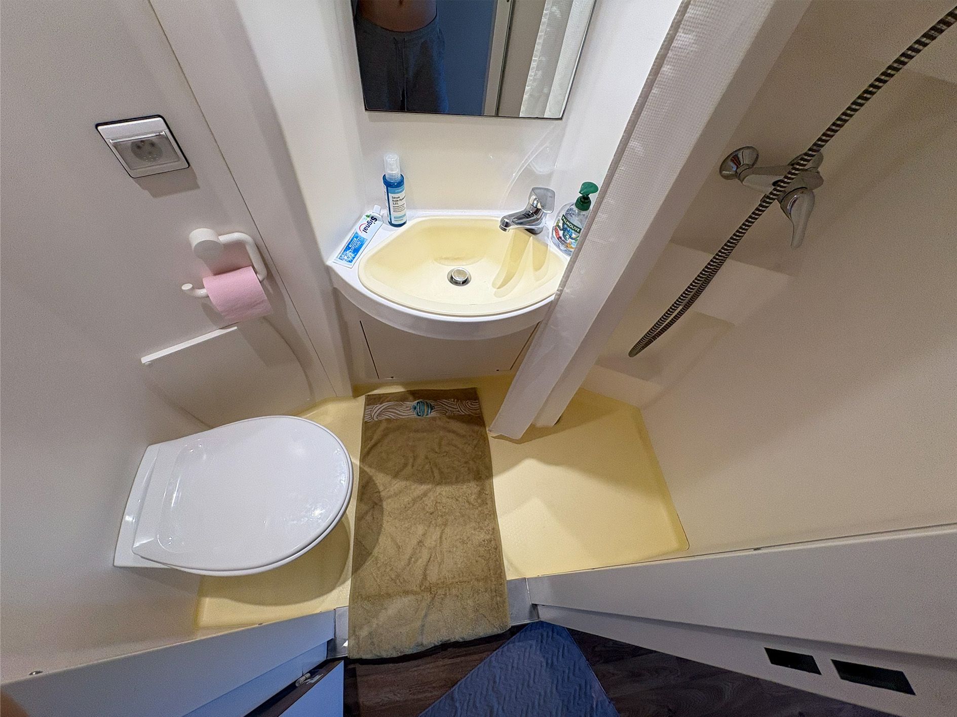 Kleines Badezimmer in einem französischen Studierendenwohnheim mit Waschbecken, Toilette und Dusche.
