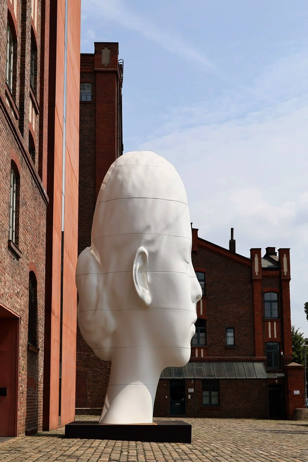 Jaume Plensas „Flora“ vor dem MKM Die mehr als sieben Meter hohe weiße Kopfskulptur „Flora“ von Jaume Plensa steht zwischen den Backsteingebäuden des Museum Küppersmühle in Duisburg.