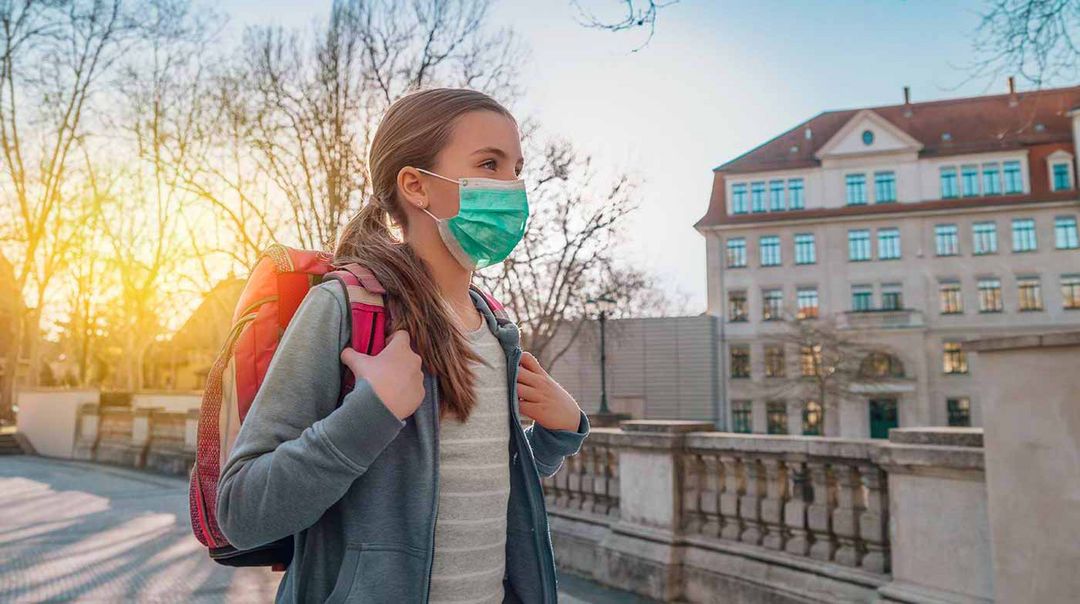 Schülerin vor Schule mit Maske