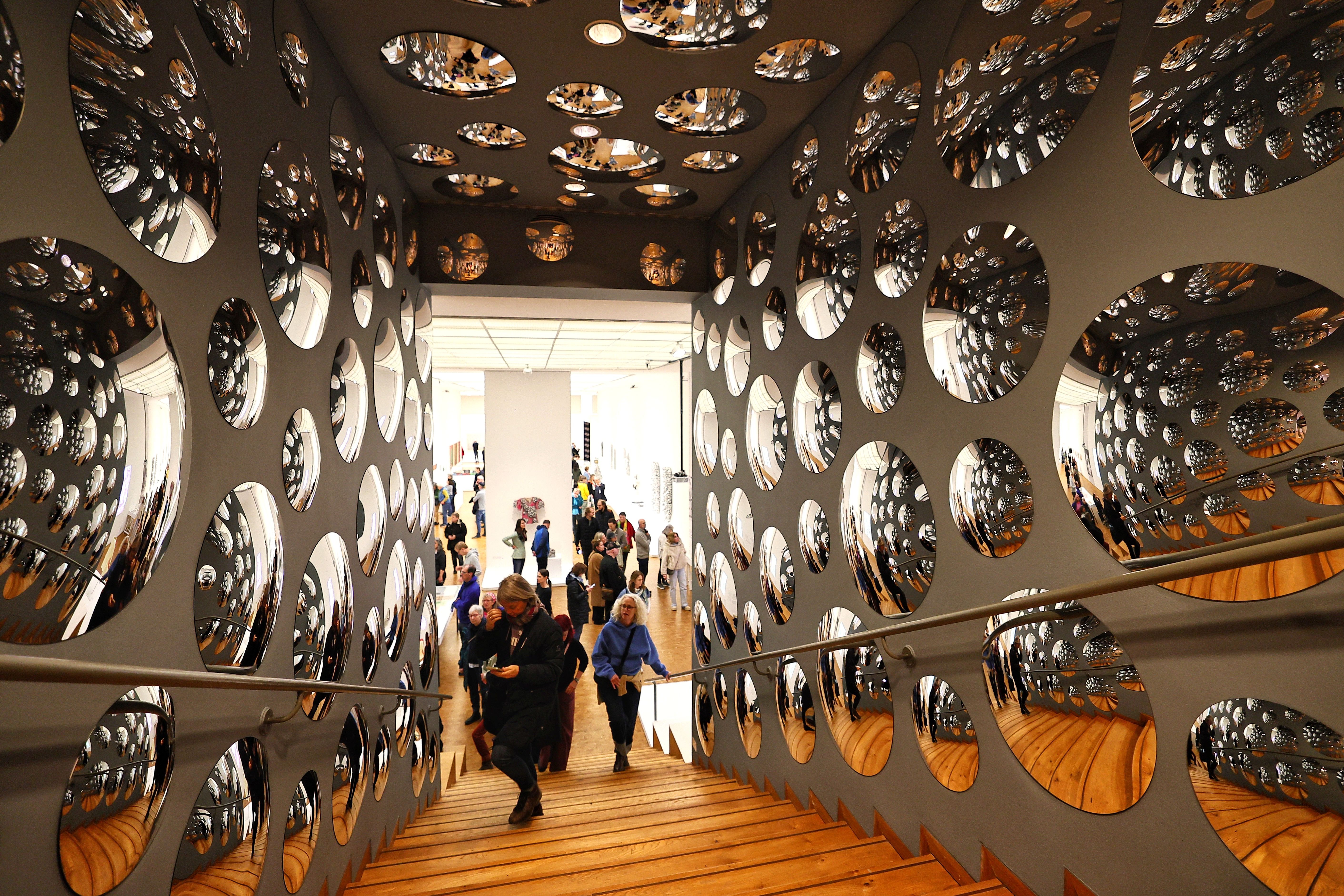  Besucher auf einer Treppe im Museum Ludwig, umgeben von ovalen Spiegelobjekten in der Kusama-Retrospektive Köln 2026