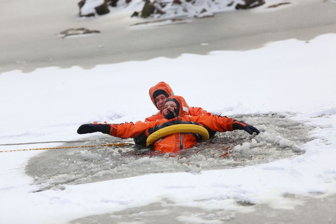 Feuerwehr übt den Ernstfall: Ausgerüstet mit Schutzkleidung bricht ein Düsseldorfer Feuerwehrmann absichtlich ins Eis ein, um die Eisrettung zu simulieren, ein gesicherter Retter hält ihn über Wasser © Landeshauptstadt Düsseldorf/Archivbild: Ingo Lammert 