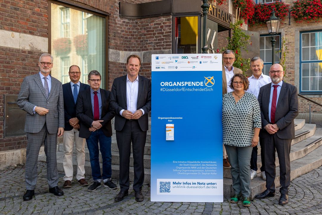 Gemeinsam für den Organspendeausweis. Die Beteiligten der stadtweiten Kampagne #DüsseldorfEntscheidetSich: (v.l.) Prof. Dr. Dr. Frank Schneider (Vorstandsvorsitzender und Ärztlicher Direktor, Uniklinik Düsseldorf), Daniel Schrader (Organspendekoordinator, Uniklinik Düsseldorf), Dr. André Schumacher (Hausarzt und Vorsitzender der Kreisstelle Düsseldorf der Kassenärztlichen Vereinigung Nordrhein), Oberbürgermeister Dr. Stephan Keller (Schirmherr der Kampagne), Michael Laumen (Präsident des Comitee Düsseldorfer Carneval e.V.), Konstanze Birkner (Geschäftsführerin des Netzwerks Organspende NRW e.V.), Andreas Preuß (Manager von Borussia Düsseldorf) und Dr. Scott Oliver Grebe (Geschäftsführender Arzt der Deutschen Stiftung Organtransplantation in Nordrhein-Westfalen).