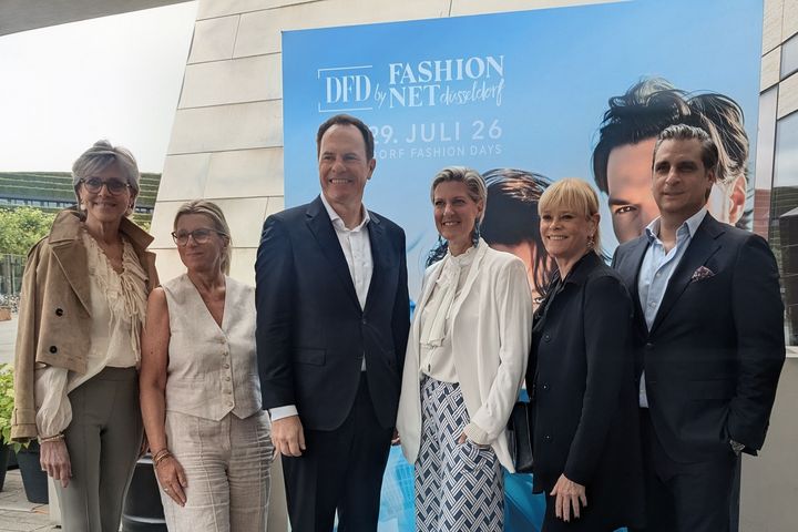 Pressekonferenz DFD by Fashion Net 2026 Sechs Personen stehen vor dem blauen Kampagnenmotiv der Düsseldorf Fashion Days 2026 auf einer Terrasse am Kö-Bogen: Ulrike Kähler, Bernadette Bitterroff, Oberbürgermeister Dr. Stephan Keller, Andrea Greuner, Mirjam Dietz und Manuel Farrokh