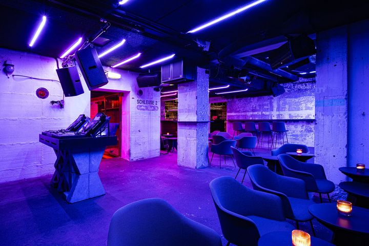 Innenraum der Schleuse Zwei im Bilker Bunker Düsseldorf mit Bar, Sitzplätzen und violett-blauer Beleuchtung