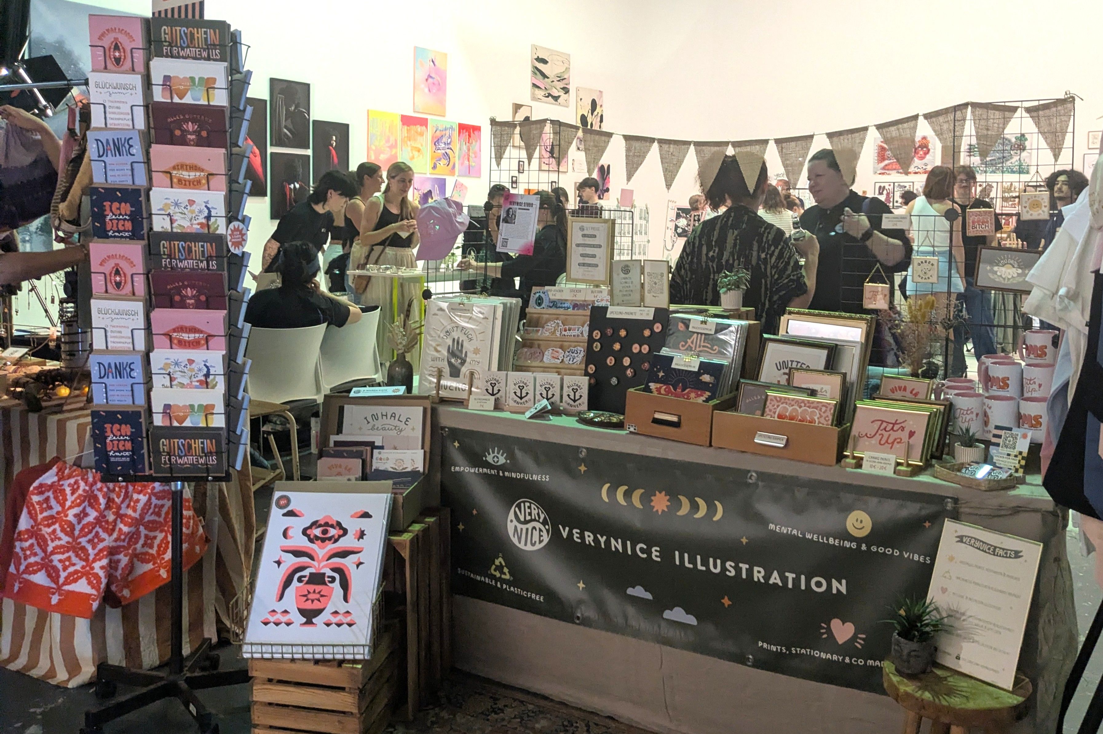 Stand von Verynice Studio mit Karten und kleinen Objekten, dahinter ein Banner mit der Aufschrift Verynice Illustration.