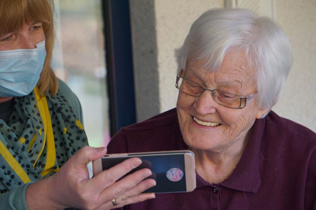 Eine junge Frau zeigt einer älteren Frau ein Handy