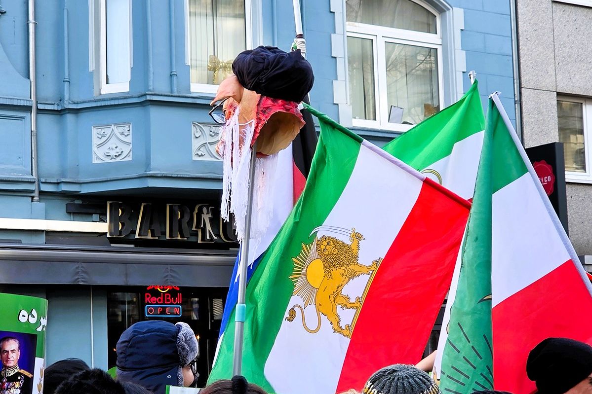 "SCHWEINEKOPF"- Demonstrierender mit iranischer Fahne und Protestsymbol bei der Iran-Demo in Düsseldorf am 24. Januar 2026.
