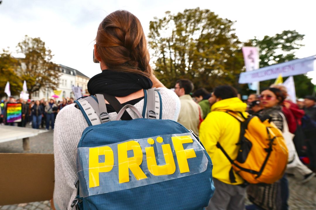 PRÜF-Demo Düsseldorf Oktober 2026 Teilnehmender mit PRÜF-Weste vor der Menschenmenge bei der Demonstration am 10. Oktober 2026 in Düsseldorf