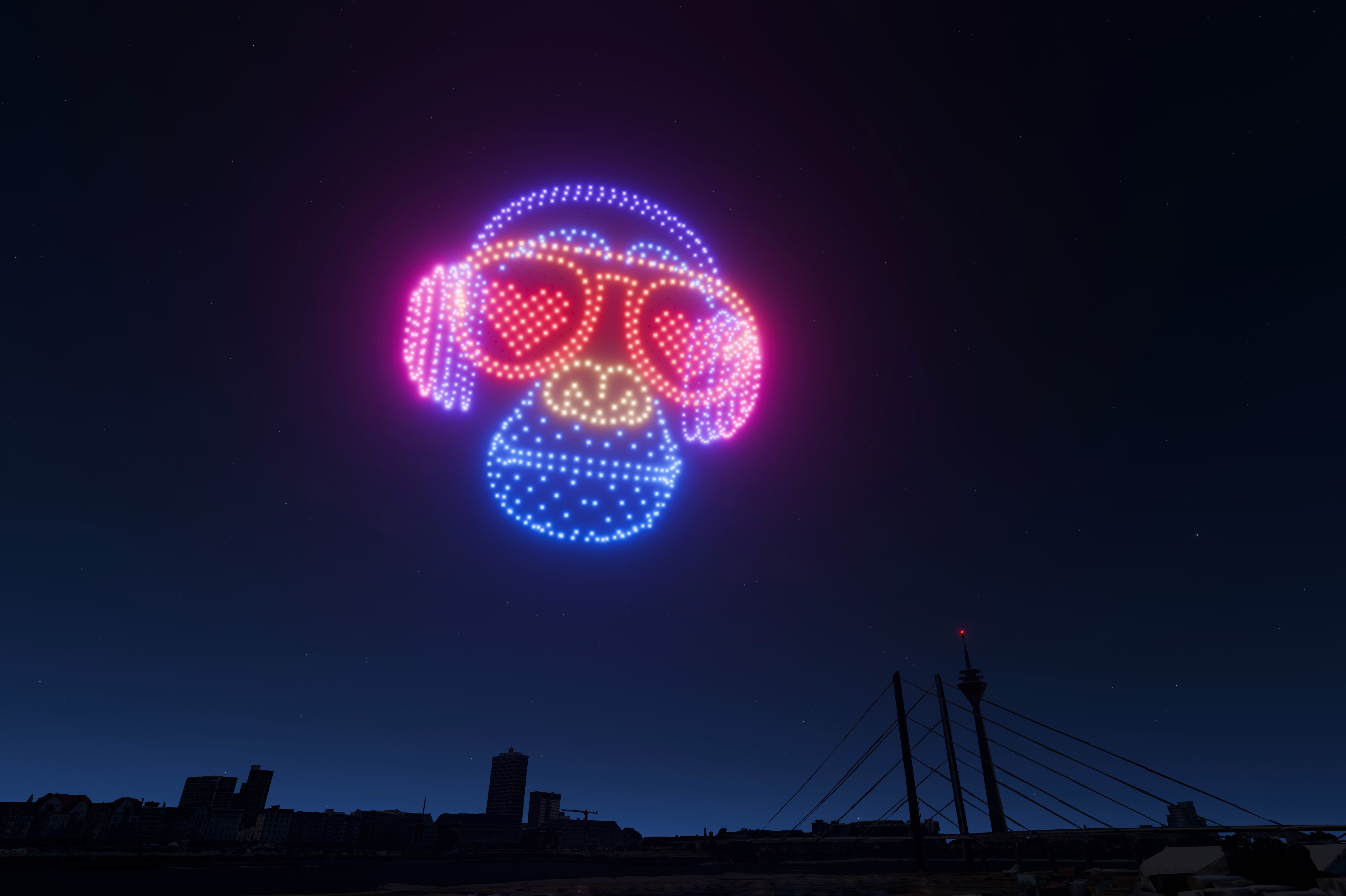 DJ-Affe mit Herzbrille: Auch humorvolle Lichtmotive gehören zur AO-Drohnenshow – hier über der Oberkasseler Brücke in Richtung Rheinturm. / Foto: AO Multimedia & Drones 