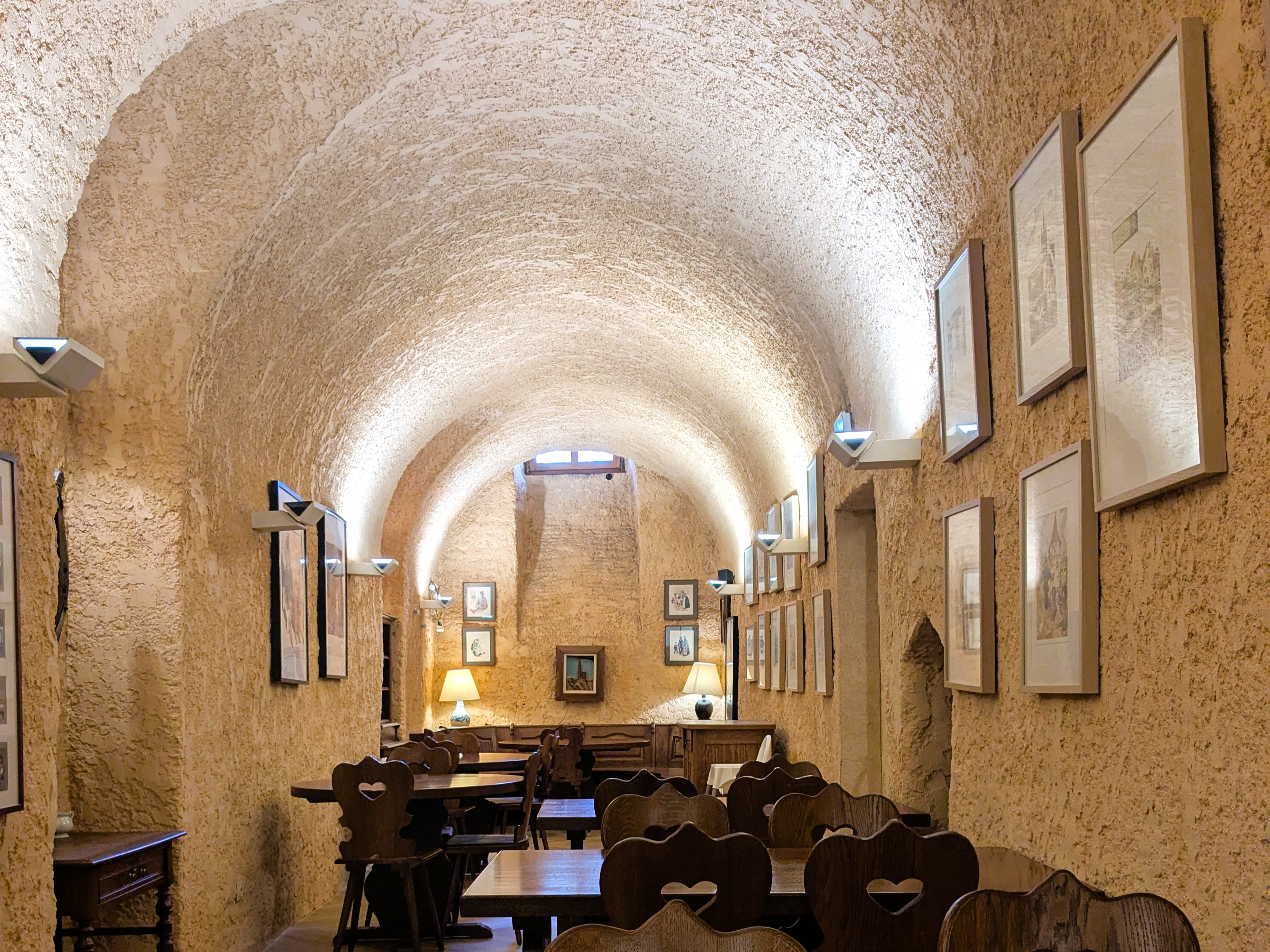 Gewölbter Frühstücksraum im Hotel Couvent du Franciscain in Straßburg mit Holztischen und Stühlen, warmes Licht.