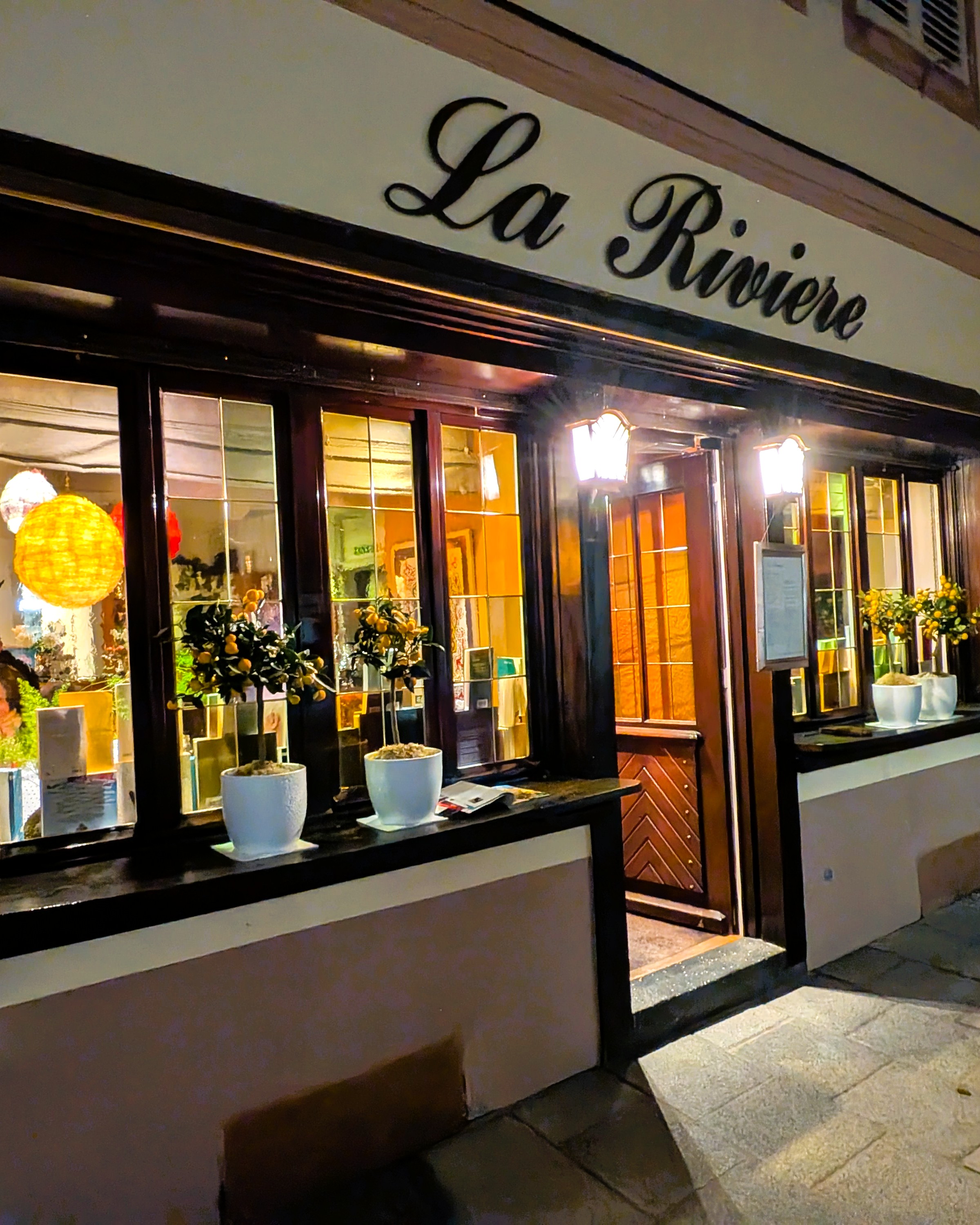 Beleuchteter Eingang des Restaurants La Rivière in Straßburg bei Nacht.