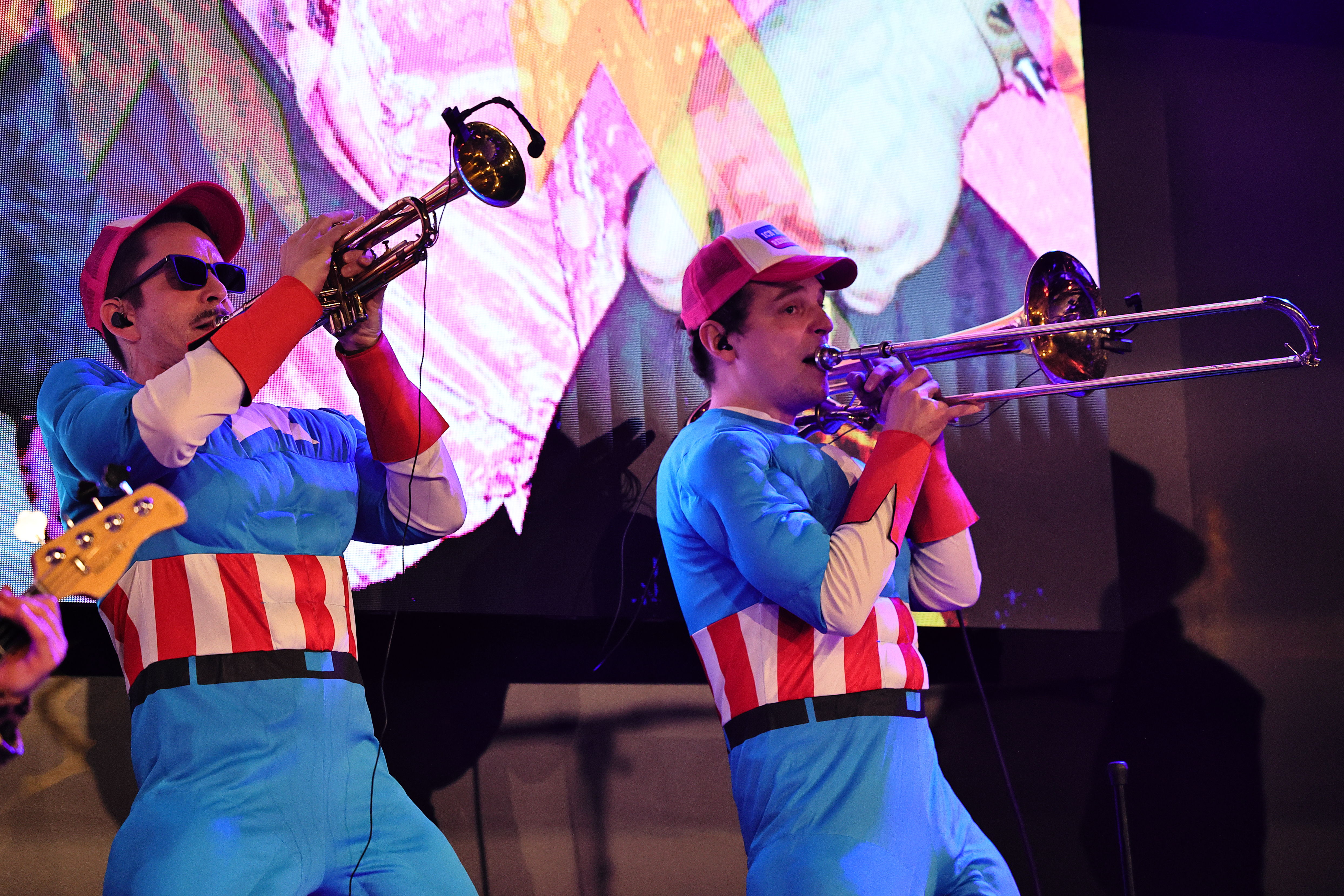 Zwei Musiker in blau-roten Kostümen spielen Trompete und Posaune.