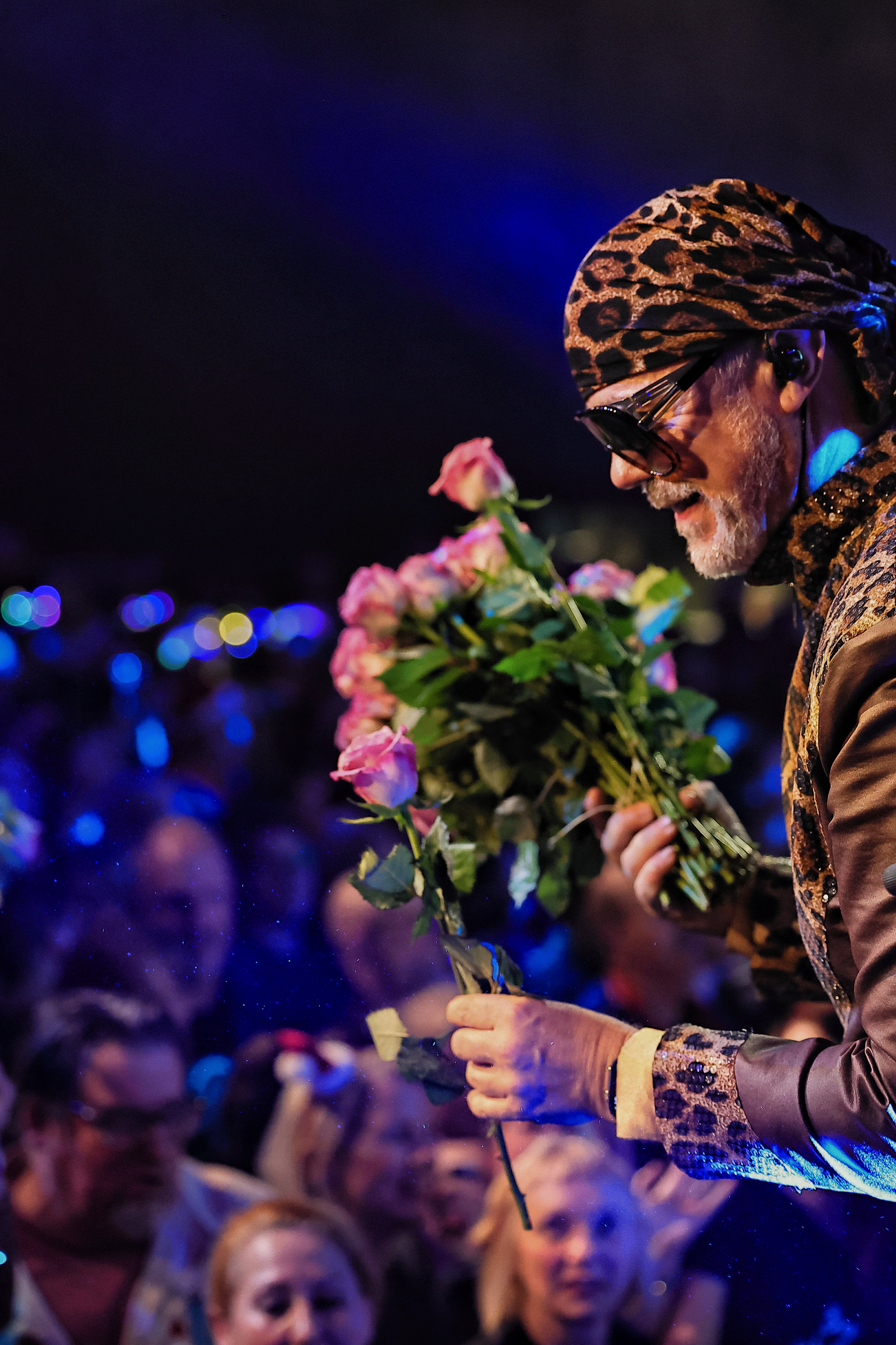 Performer mit Blumenstrauß wird auf der Bühne gefeiert, Publikum dahinter.